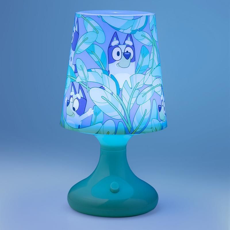 Egy türkizkék lámpa Bluey karakterekkel, a lombozat közepén. Az alap türkiz, az árnyékoló világoskék, rajzolt kutyákkal és levelekkel.