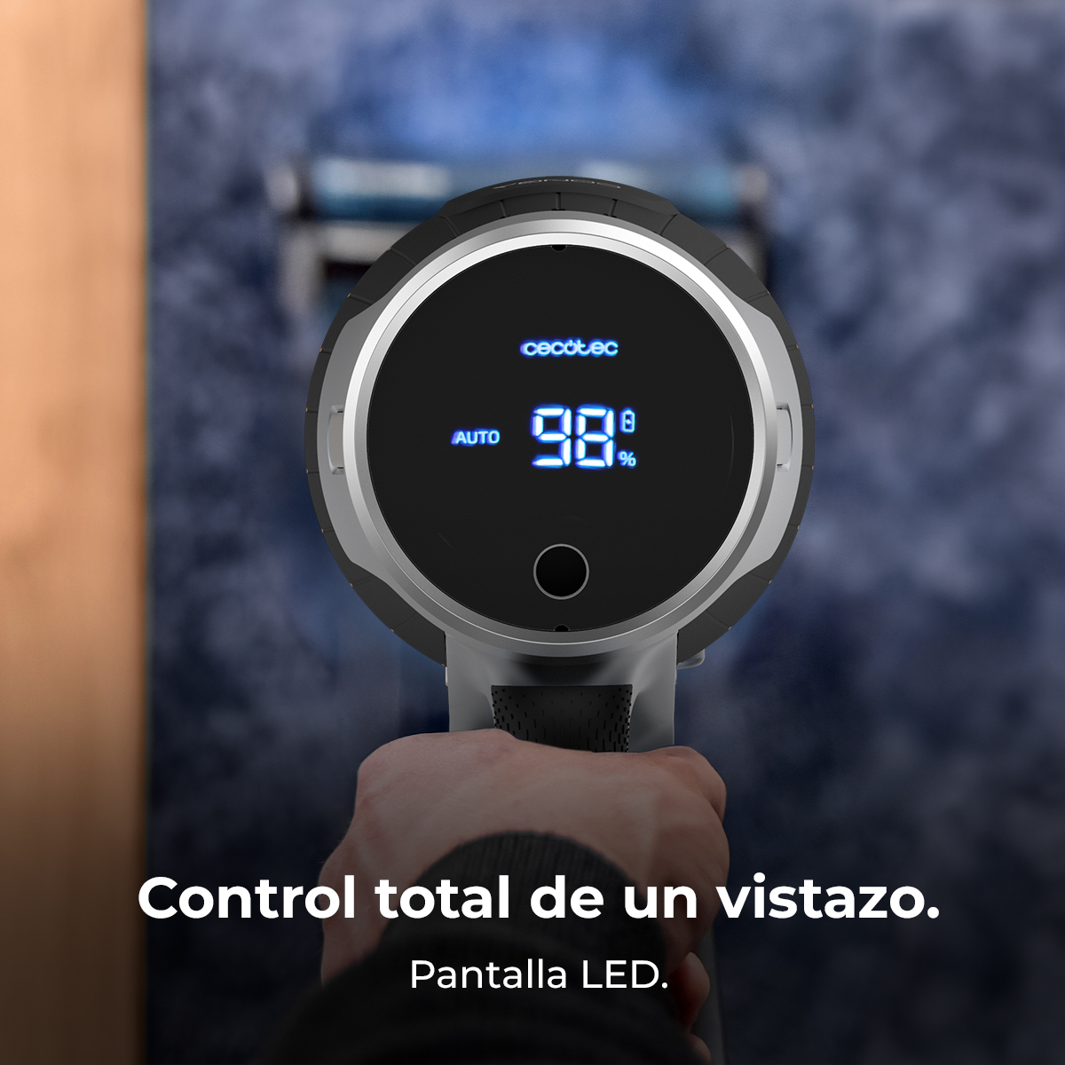 Primer plano de la pantalla de una aspiradora que muestra el 98%. Mano sosteniendo el dispositivo. Texto abajo: 'Control total... Pantalla LED'.