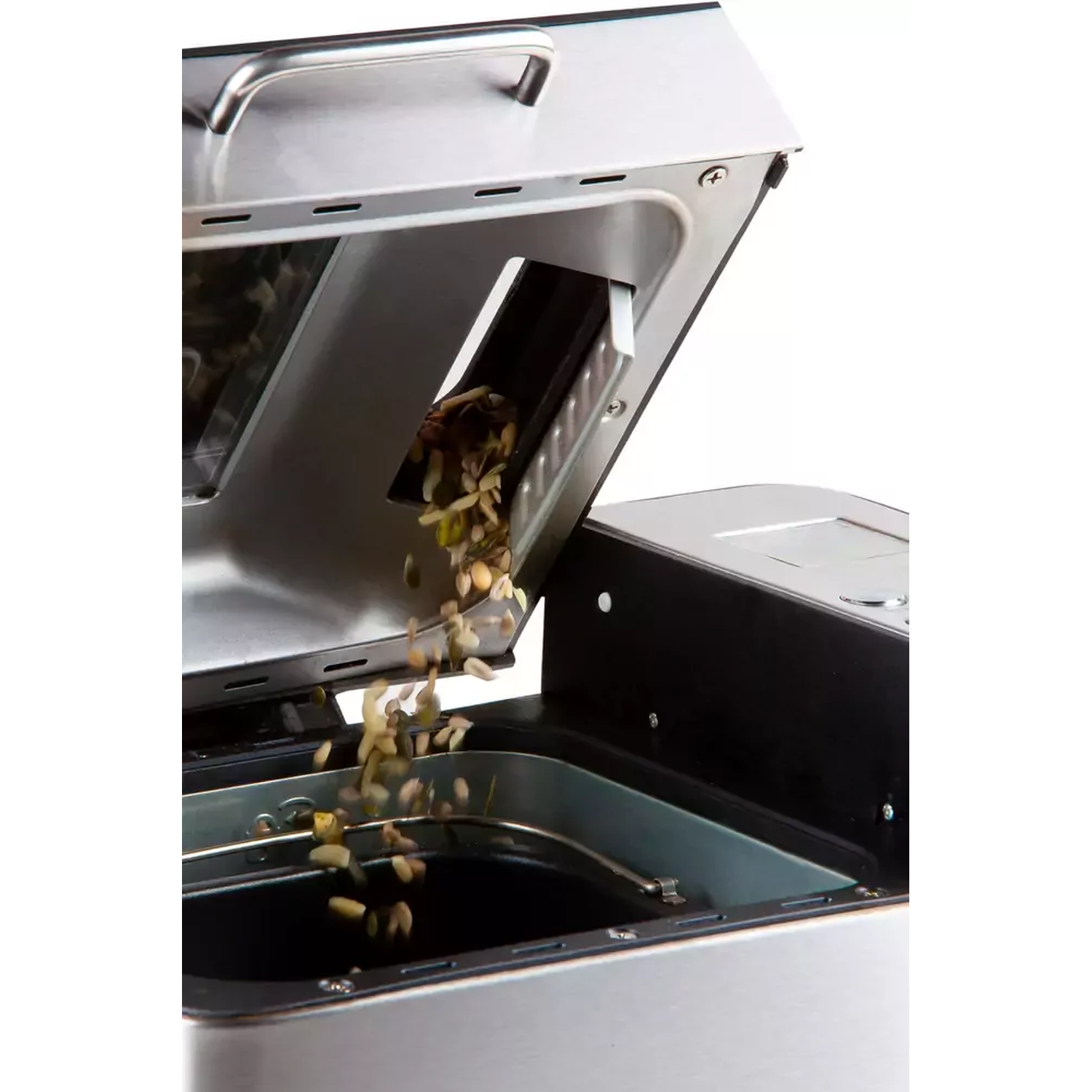 Een broodbakmachine met deksel open. Noten vallen uit een dispenser in de bakvorm. De machine is zilver en zwart.