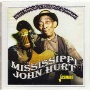 Mississippi John Hurt, Gitarre und Mikrofon haltend, lächelnd. Text: Ain't Nobody's Doggone Business.