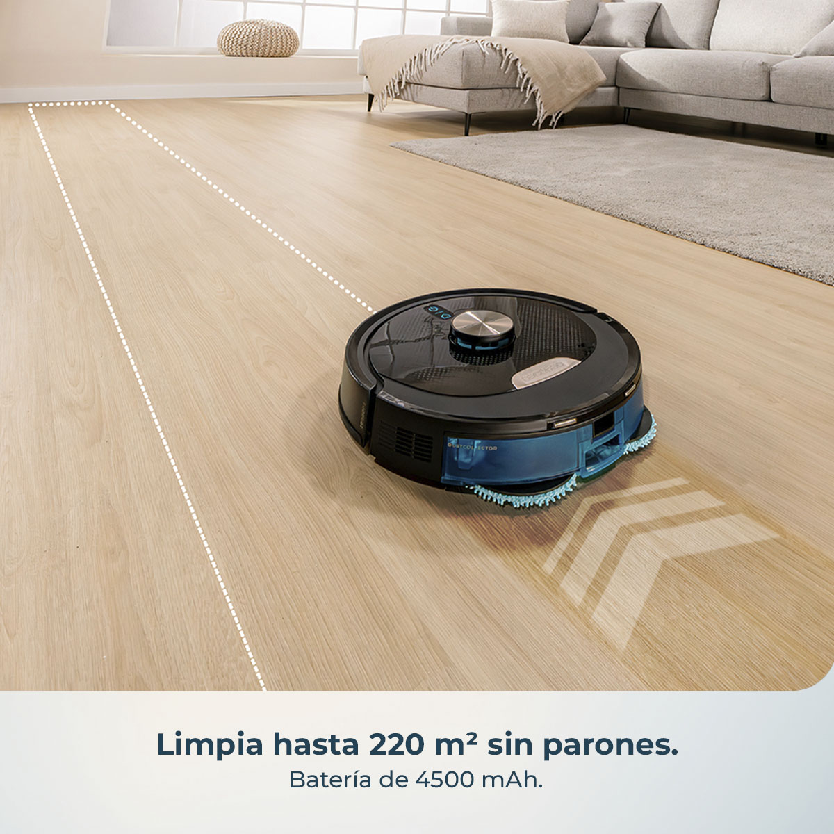 Una aspiradora robot negra y azul en un piso de madera. Un sofá y una alfombra grises están en el fondo, cerca de una ventana.