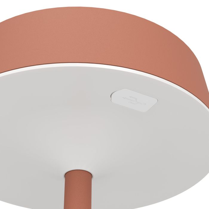 Nahaufnahme einer Lampe. Die Oberseite ist terrakottafarben, die Unterseite ist weiß mit einem USB-Anschluss. Eine Terrakotta-Säule trägt die Lampe.