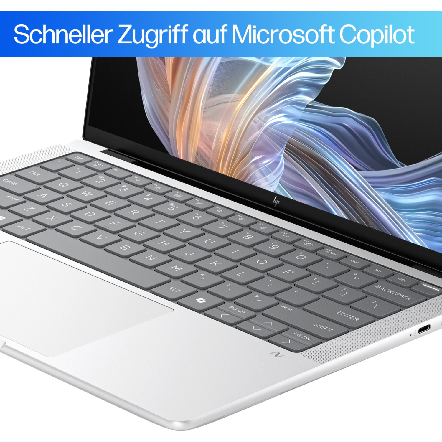 A laptop with a gray keyboard and a white body is open. The screen shows a colorful, abstract design.
