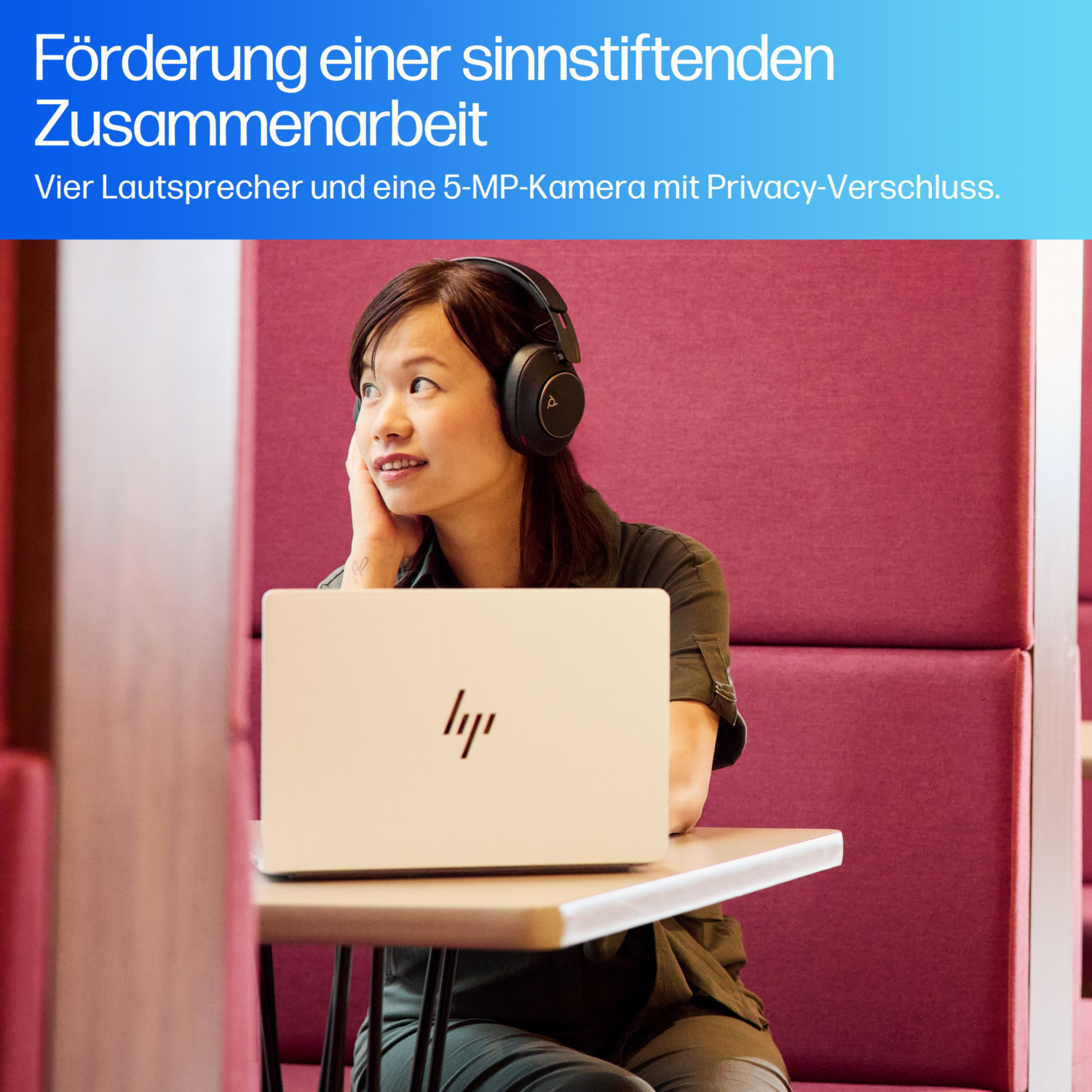 Woman wearing headphones looks at laptop in a booth. The laptop is white, the booth is magenta, and the background is blurred.