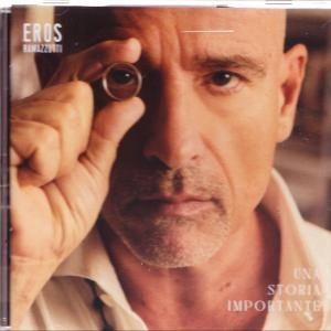 Ein Mann mit Glatze hält einen Ring vors Auge. Das Albumcover zeigt 'Eros' und 'Una Storia Importante'.