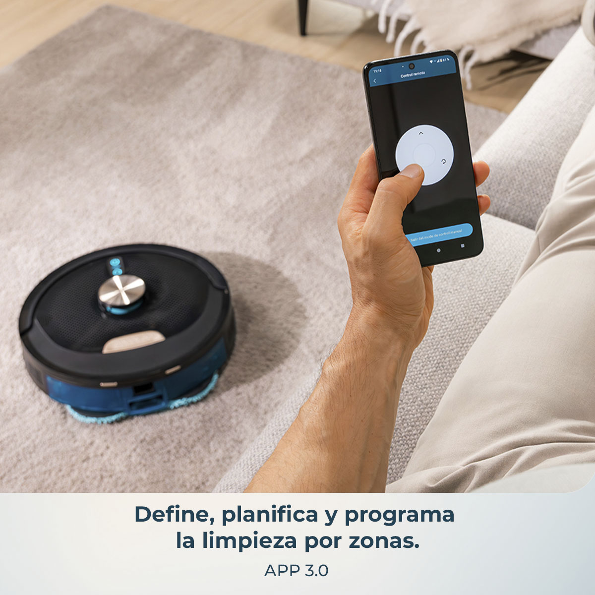Una persona sosteniendo un teléfono controlando una aspiradora robot en una alfombra. El teléfono muestra opciones de control. APP 3.0.