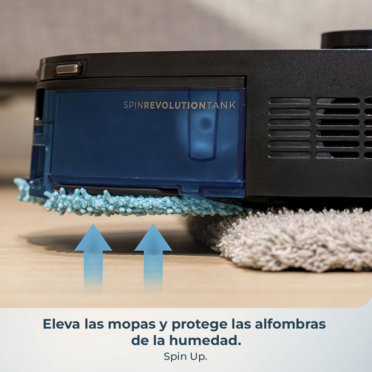 Primer plano de un robot de limpieza negro y azul con un depósito de agua azul. Flechas apuntan hacia arriba desde la almohadilla de limpieza. El suelo es de madera.