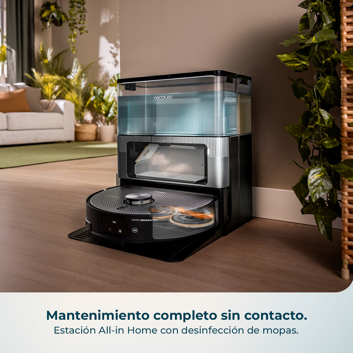 Una aspiradora robot negra y plateada con una estación de limpieza. Plantas y un sofá en el fondo.