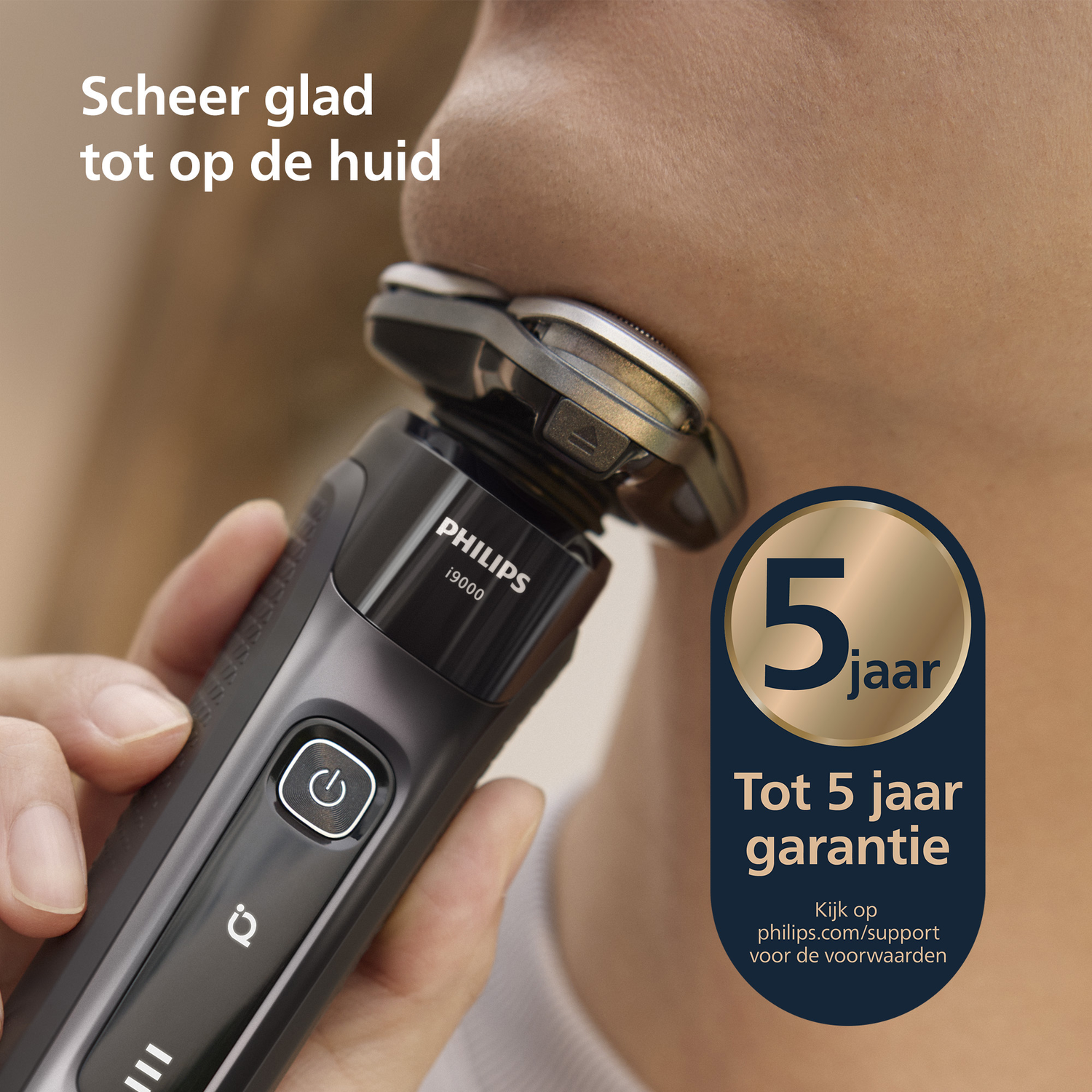 A man shaves with a Philips electric shaver. The shaver is black and silver. A blue and gold badge says '5 year warranty'.