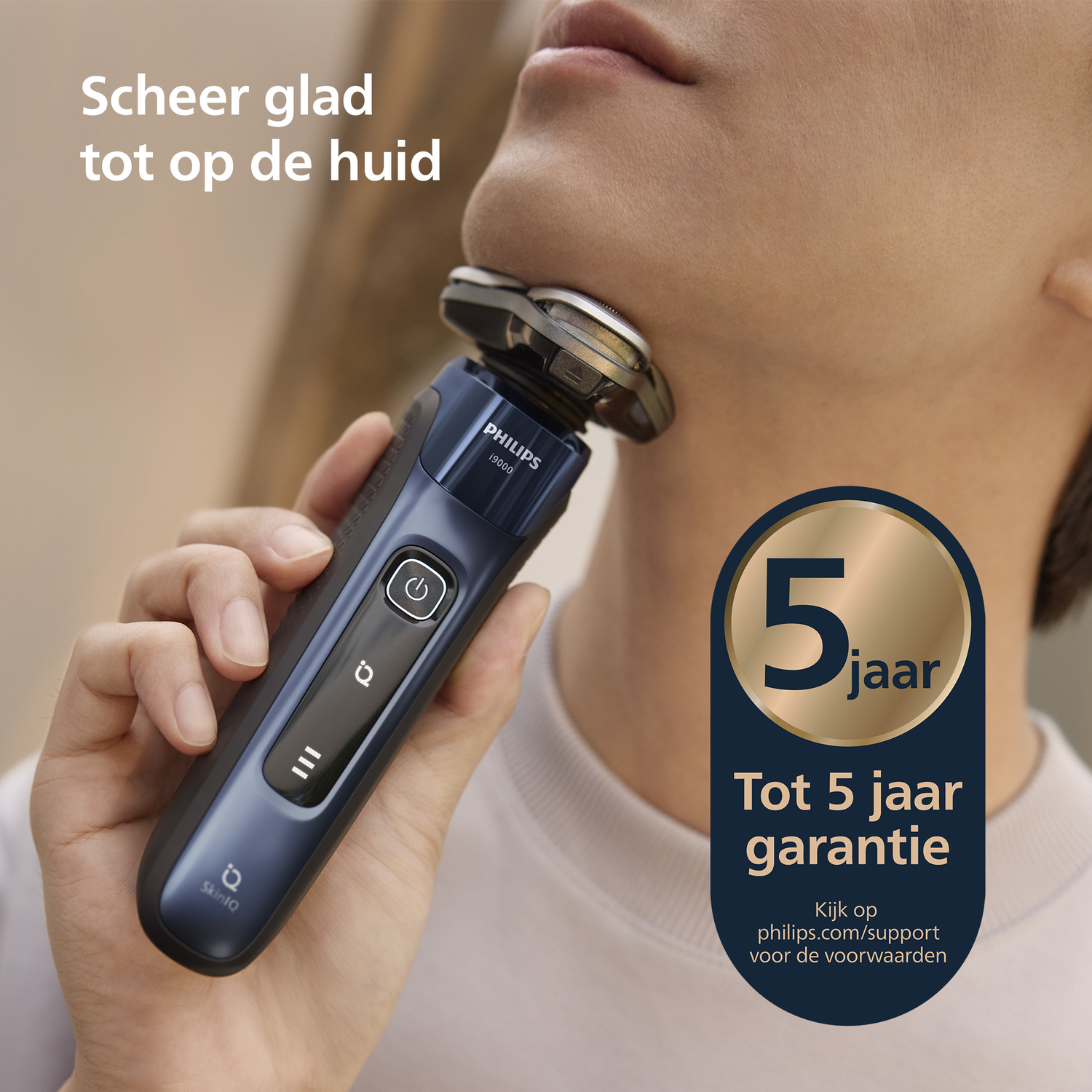 Een persoon scheert zich met een Philips elektrisch scheerapparaat. Tekst: 'Scheer glad tot op de huid' en '5 jaar garantie'.