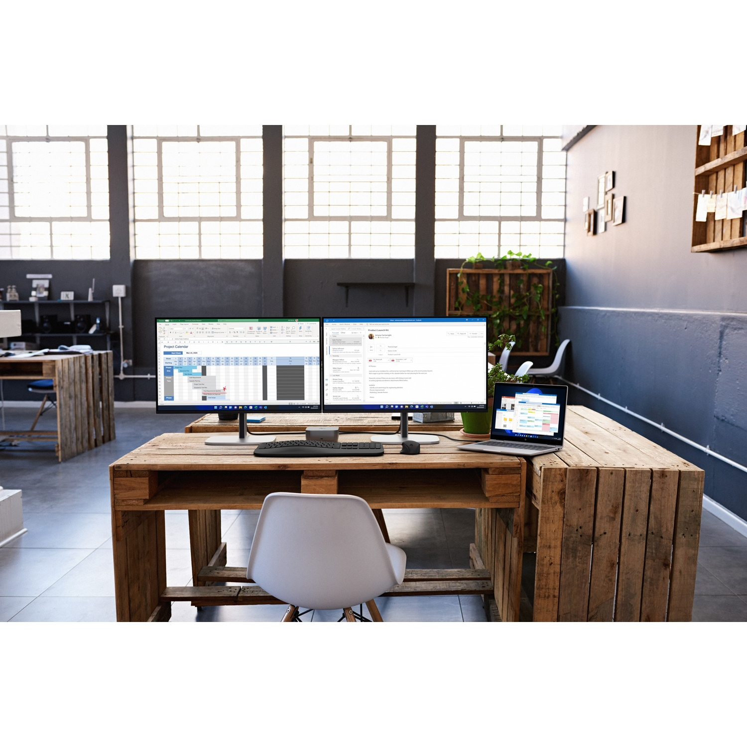 Kantoorwerkplek met twee monitoren, een laptop en een toetsenbord op een houten bureau. Een witte stoel ervoor.