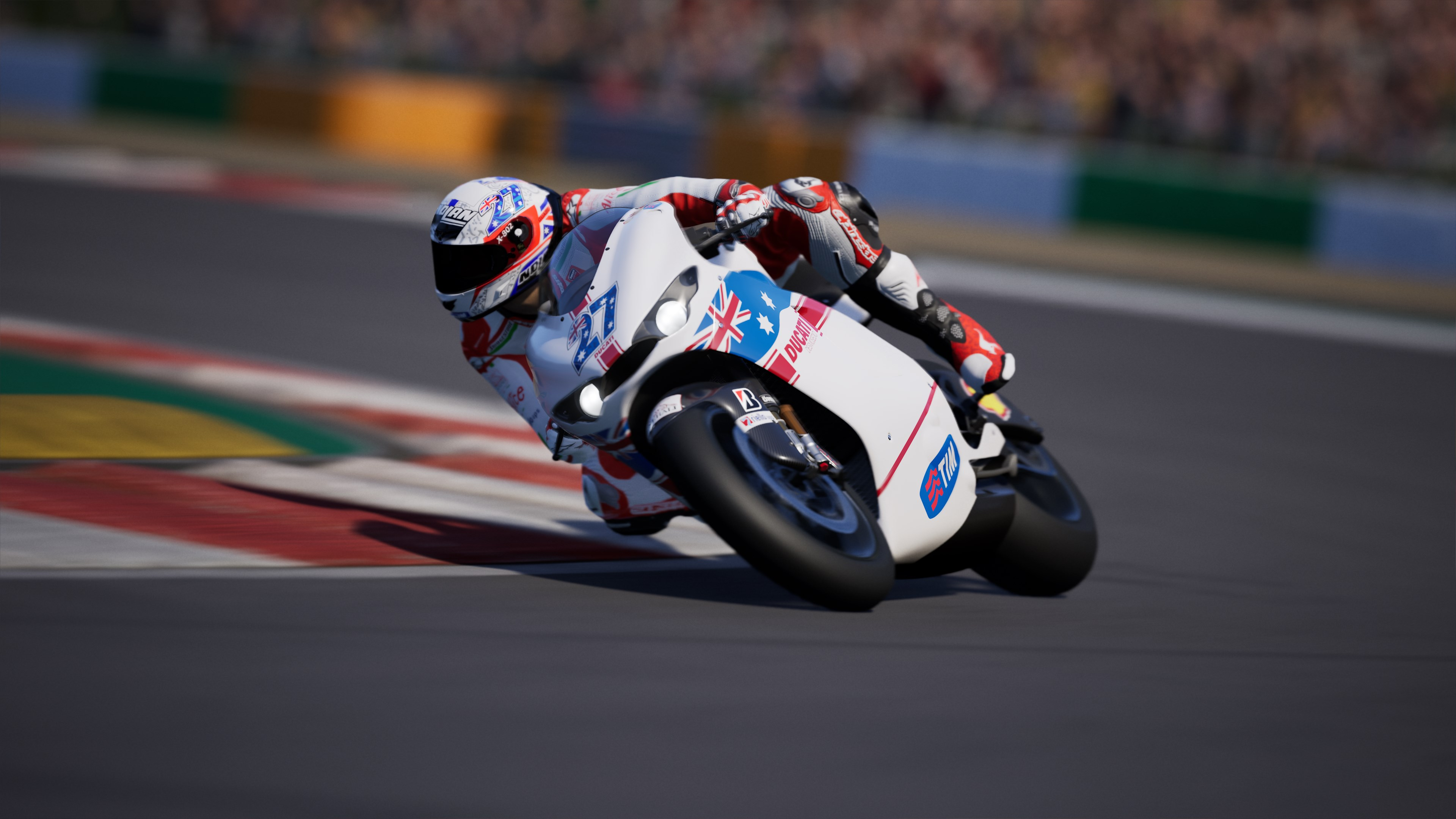 Un pilote sur une moto Ducati blanche s'incline dans un virage sur la piste. La moto a un drapeau australien.