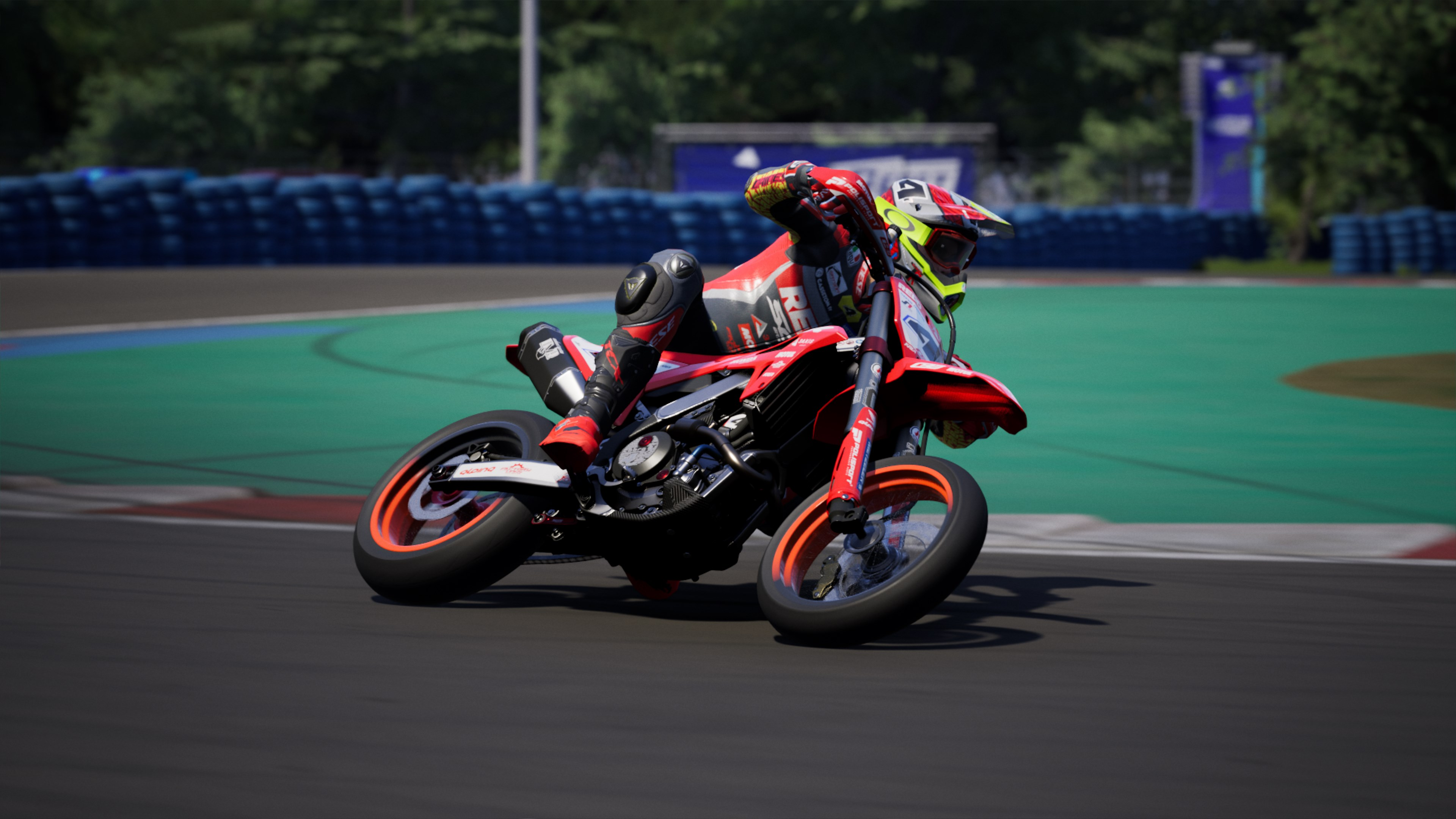 Un motocycliste se penche dans un virage sur la piste. La moto rouge a des roues noires et un casque jaune.