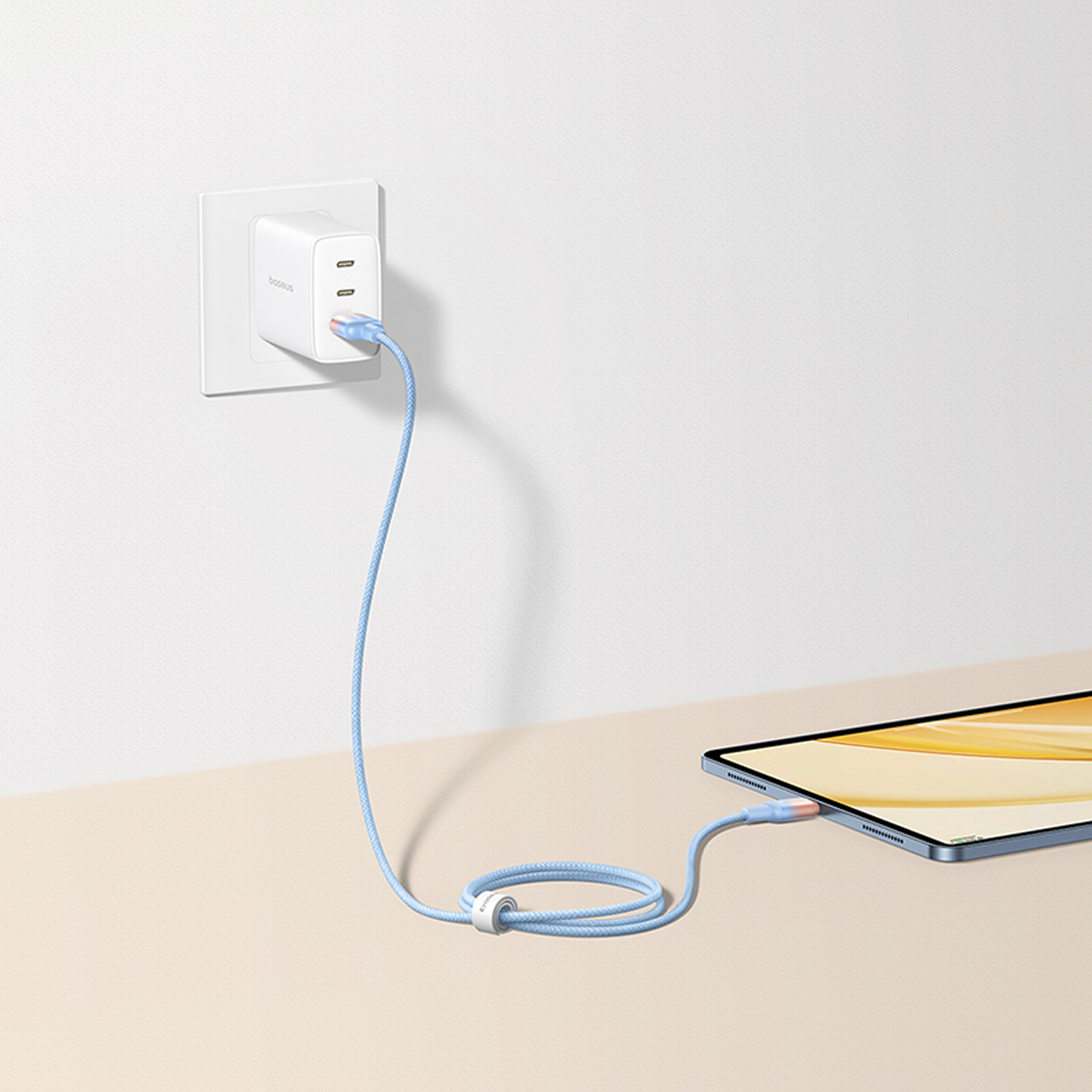 Una tableta se está cargando con un cable azul conectado a un cargador de pared blanco. El cable es azul claro.