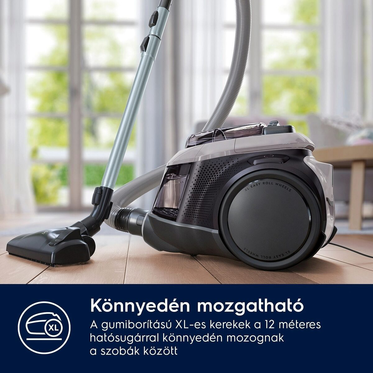 Egy fekete-szürke porszívó fa padlón. A szöveg XL Easy Roll Wheels. Alatta magyar szöveg található.