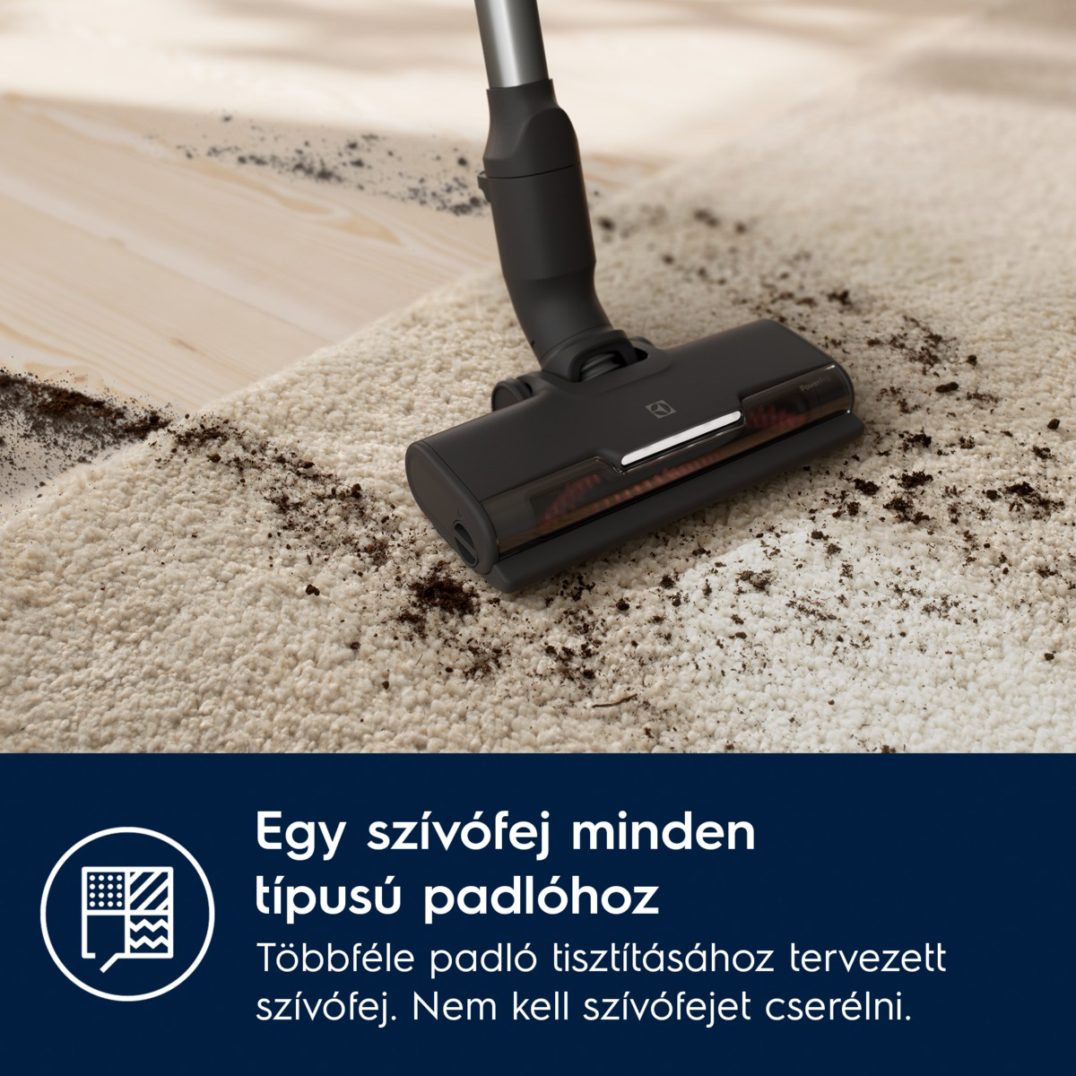 Egy fekete porszívófej tisztít egy piszkos, bézs szőnyeget, melyen szennyeződés van. Fa padló a háttérben.
