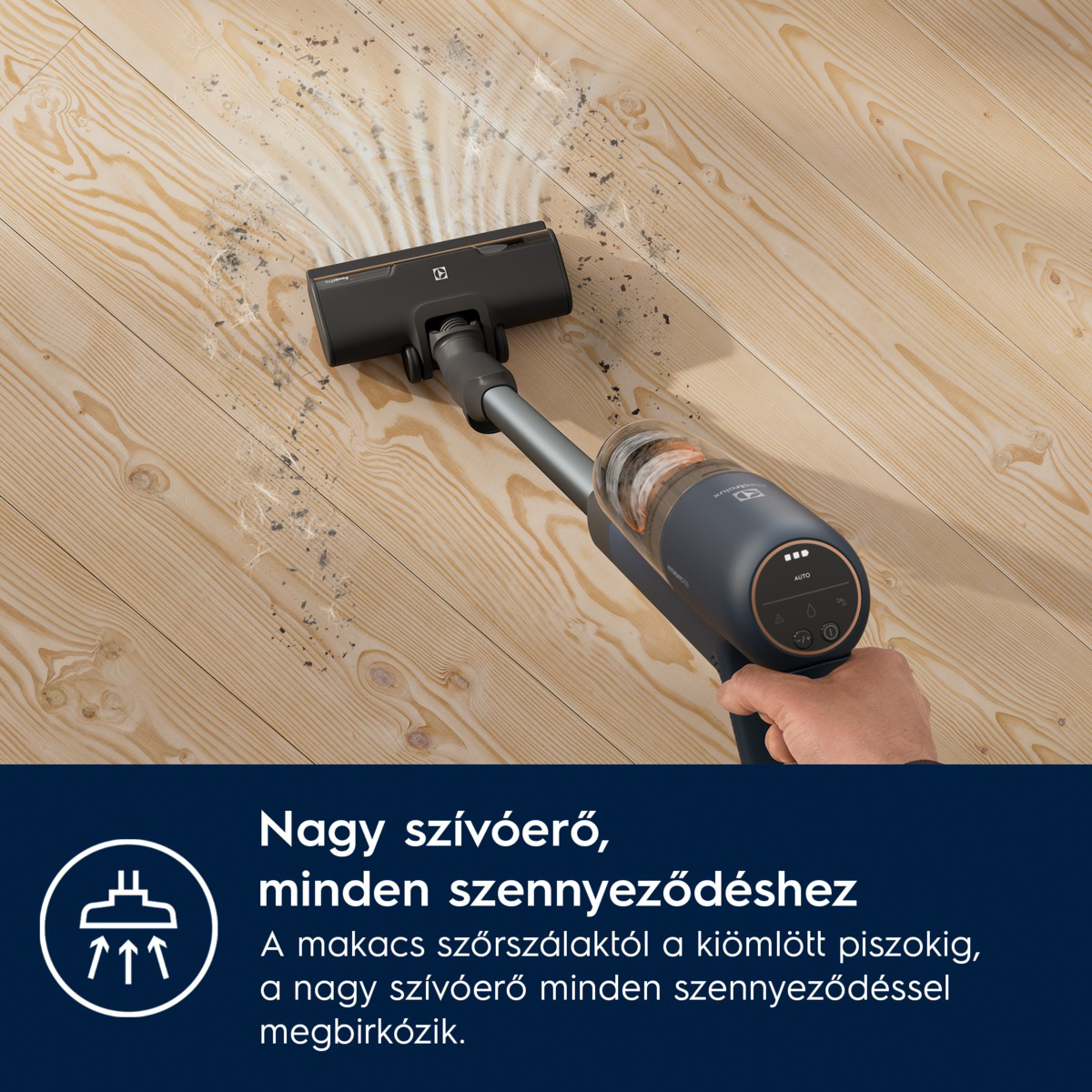 Egy vezeték nélküli porszívó fa padlót tisztít. A porszívó sötétszürke és ezüst színű. Törmelék látható a padlón.