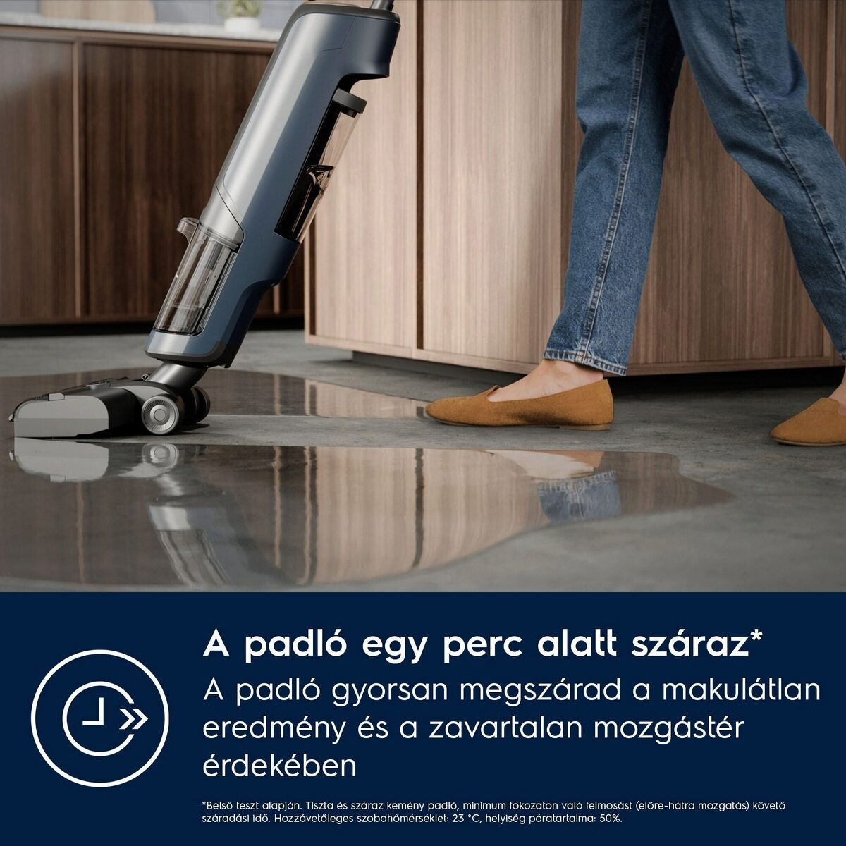 Egy személy egy nedves padlón sétál, amelyet egy kék tisztítószerrel tisztítottak. A padló és a tisztítószer az előtérben, a személy a háttérben.
