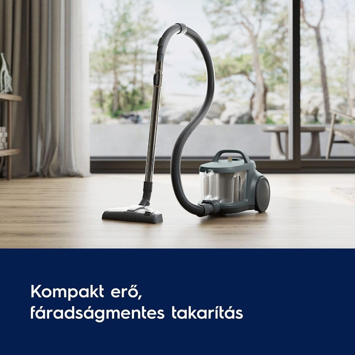 Egy szürke porszívó egy fa padlón áll egy ablak közelében. A háttérben fák és napsütés láthatók.