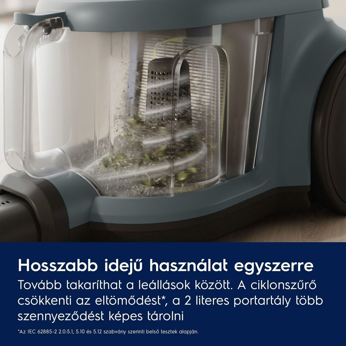 A porszívó portartályának közeli képe. Átlátszó, törmelék van benne. A porszívó türkiz és fekete. Szöveg alul.