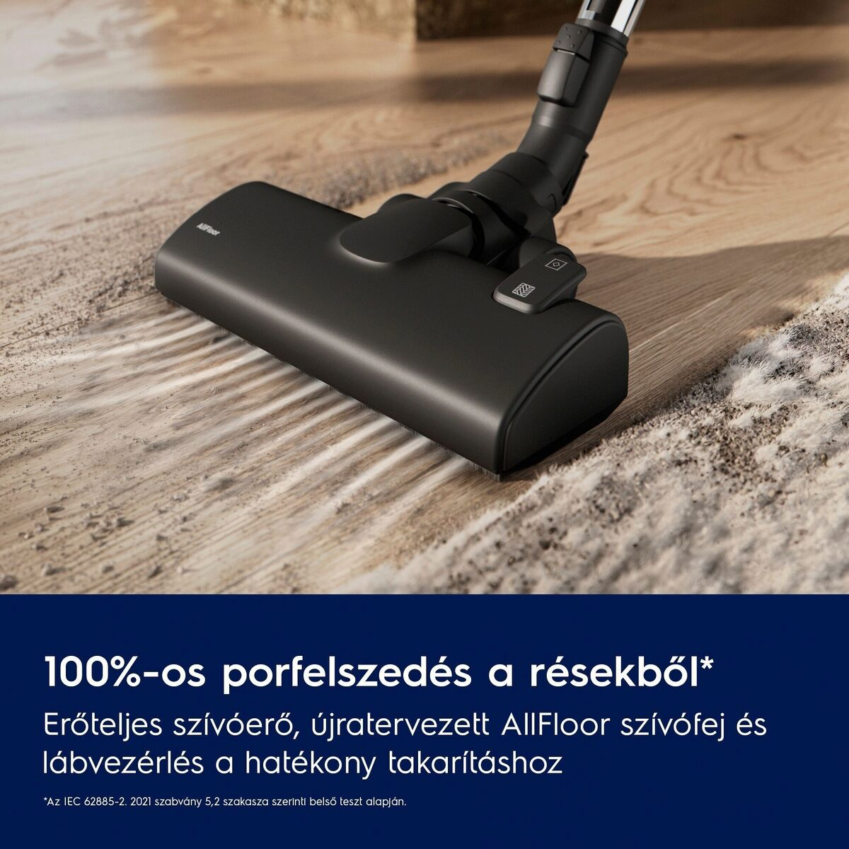 Egy fekete porszívófej a fa padlón, tisztítja a szennyeződést a szőnyegről. Alul szöveg: 100% por eltávolítás.