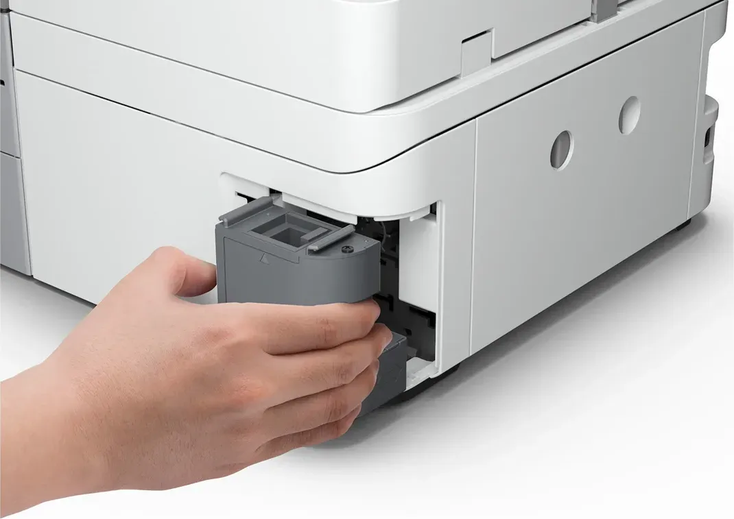 Eine Hand setzt eine graue Kartusche in einen weißen Drucker ein. Der Drucker hat ein kastenförmiges Design.