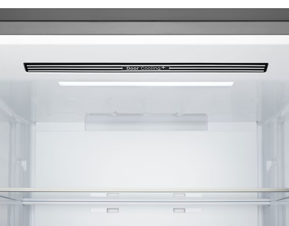 Wnętrze białej lodówki. Czarny prostokątny otwór wentylacyjny z napisem Door Cooling+ u góry. Widoczne półki i światła.