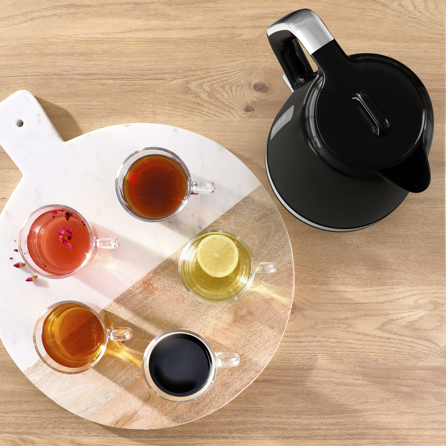 Vue aérienne d'une table en bois avec une bouilloire noire, une planche de marbre avec des tasses de thé.