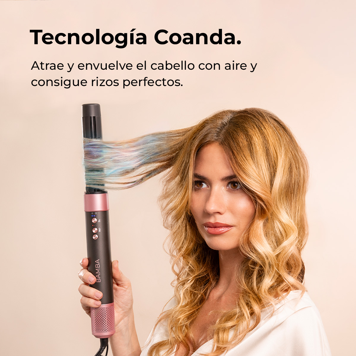 Una mujer usa un moldeador de pelo. El moldeador es negro y rosa. Su pelo es rubio y rizado. El fondo es beige.