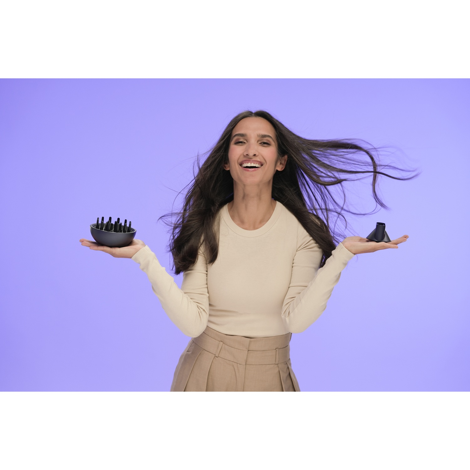 Vrouw lachend, houdt in elke hand een föhnopzetstuk. Haar wappert, draagt ​​beige top en rok, tegen een paarse achtergrond.
