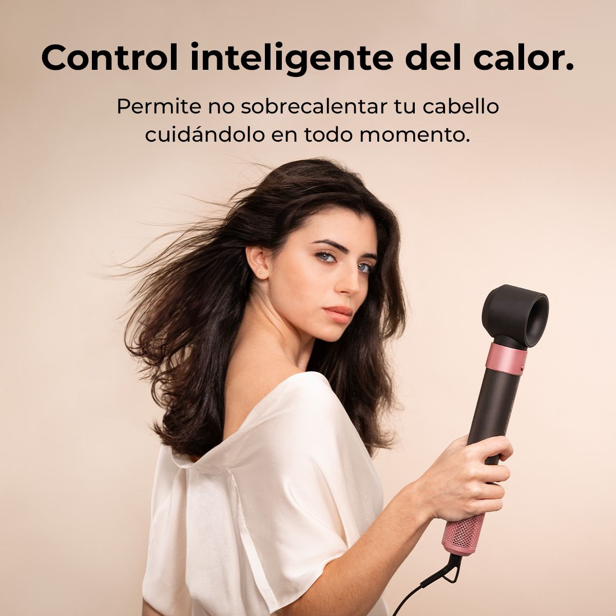 Una mujer sostiene un secador de pelo negro y rosa. Tiene cabello largo y oscuro y viste una blusa blanca. El texto dice: control inteligente del calor.