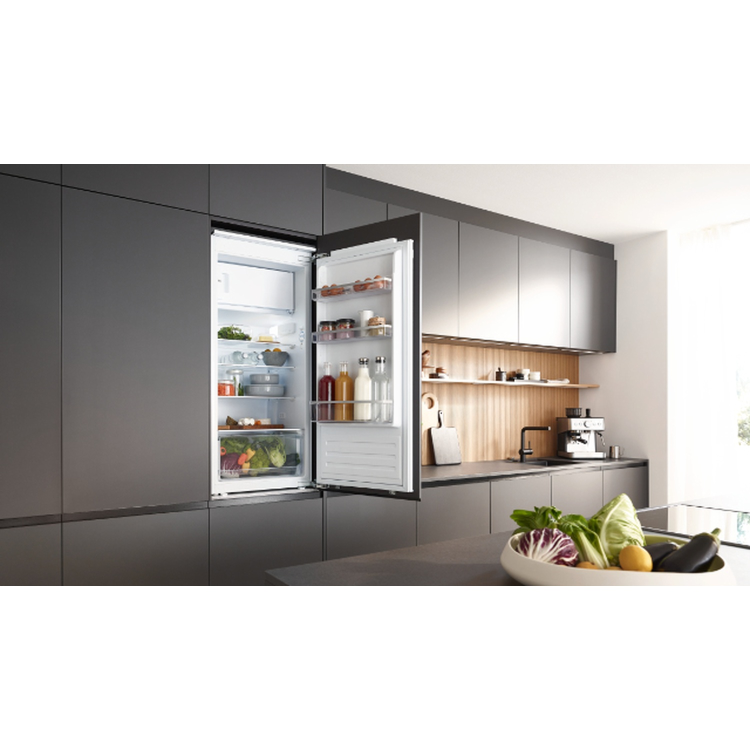 Réfrigérateur ouvert dans une cuisine moderne. Fruits, légumes et boissons à l'intérieur. Comptoir avec légumes.