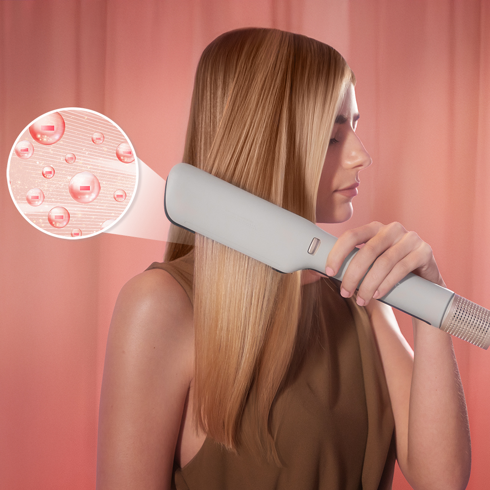 Una mujer usa una plancha de pelo gris claro en su cabello rubio. El fondo es rosa. Hay un gráfico de burbujas ampliado.