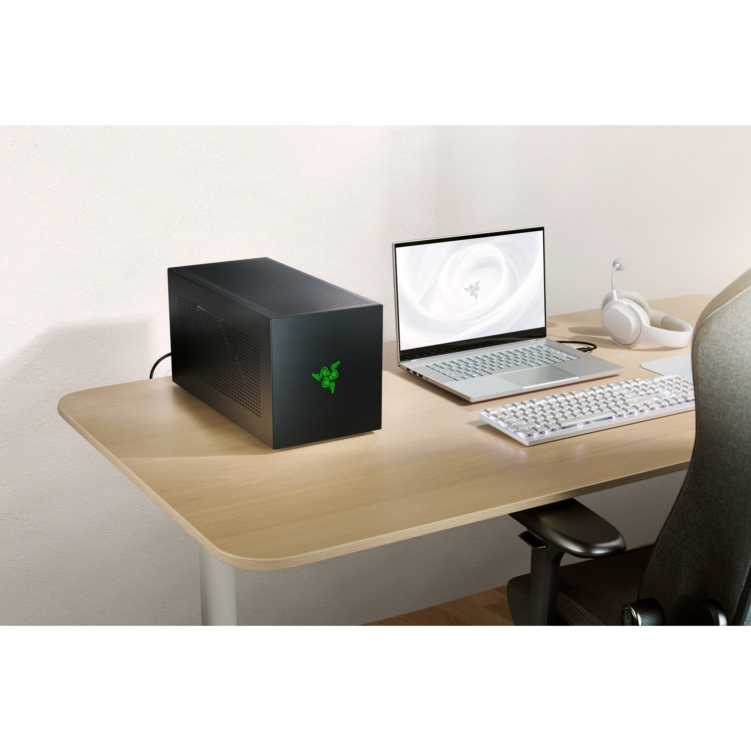 Une configuration de bureau avec un PC noir, un ordinateur portable, un clavier et un casque. Le logo Razer est sur le PC.
