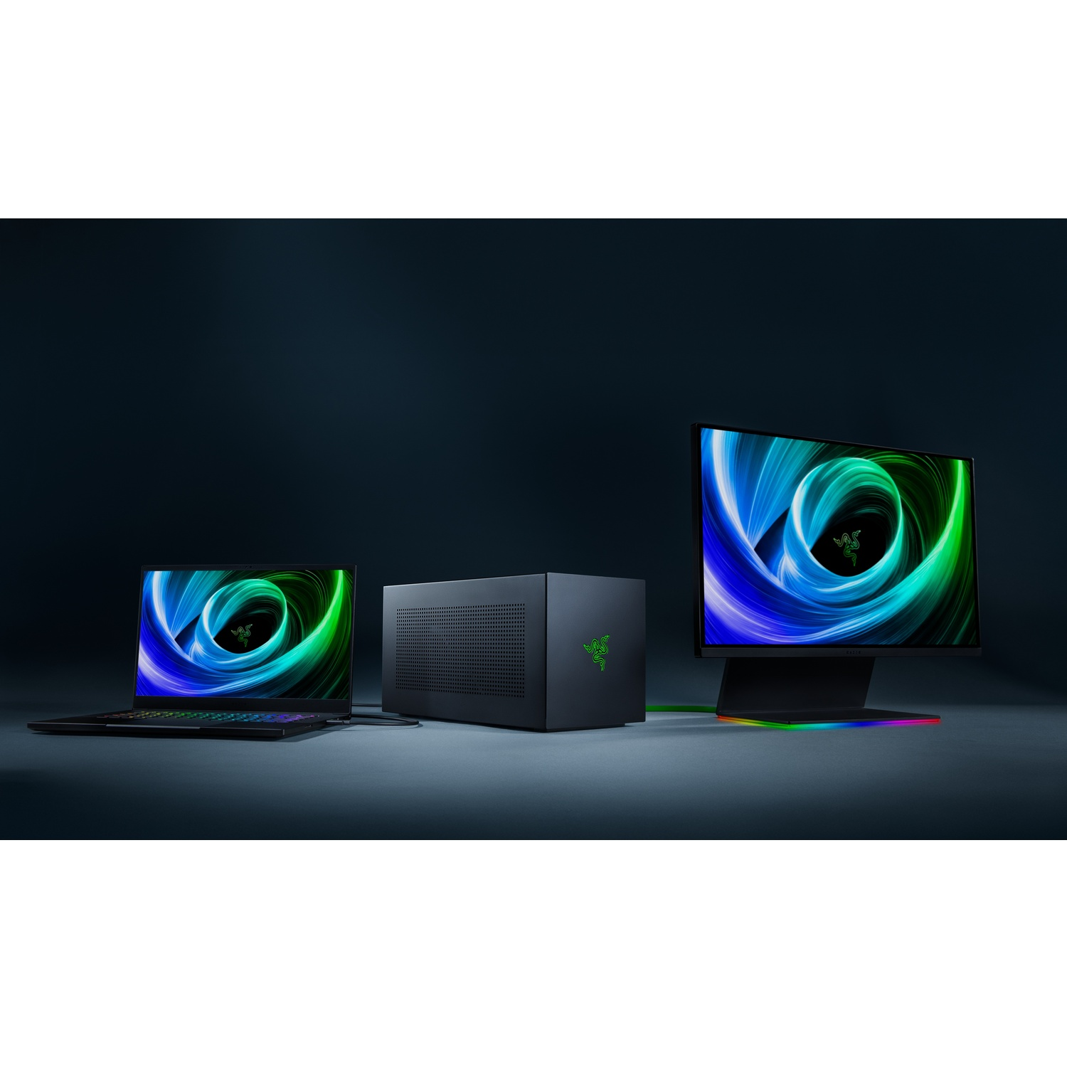 Un ordinateur portable, un PC et un moniteur noirs sont affichés, tous avec le logo Razer. Les écrans affichent un motif tourbillonnant vert et bleu.