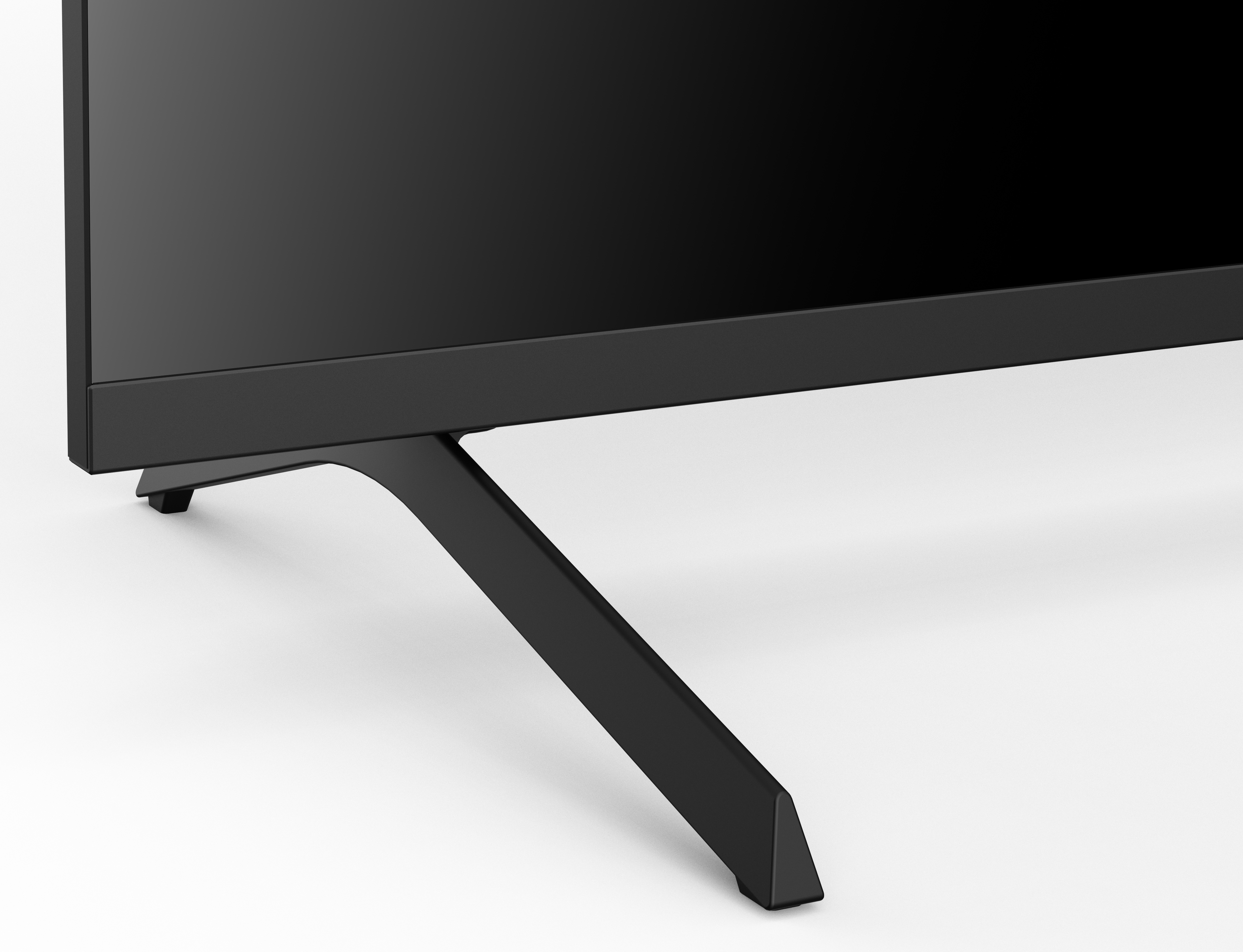 Czarna noga stojaka pod telewizor jest ustawiona pod kątem na białej powierzchni. Widoczna jest czarna rama telewizora.