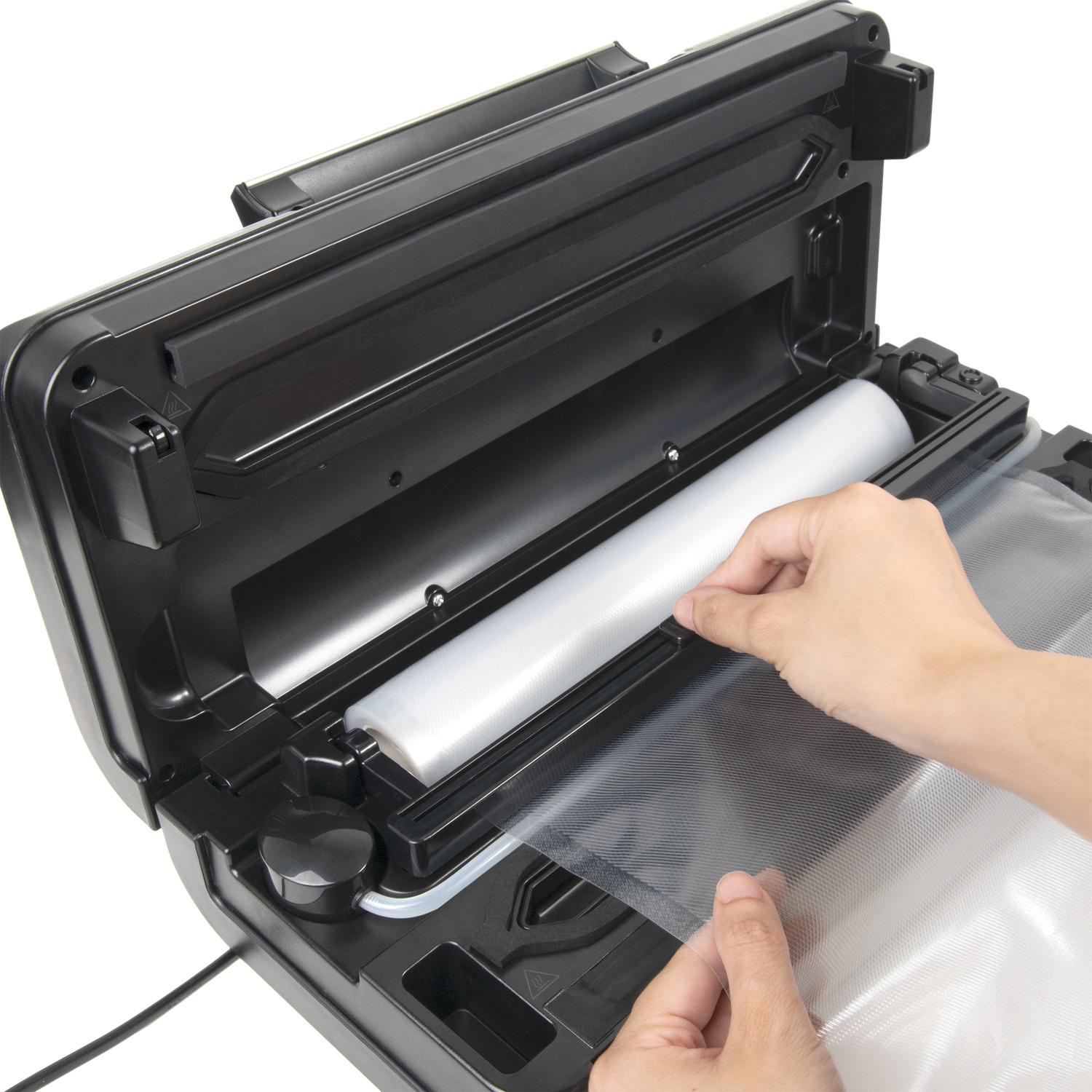 Handen plaatsen een plastic zak in een zwarte vacuümsealer. Een rol plastic is zichtbaar in het apparaat. De achtergrond is wit.