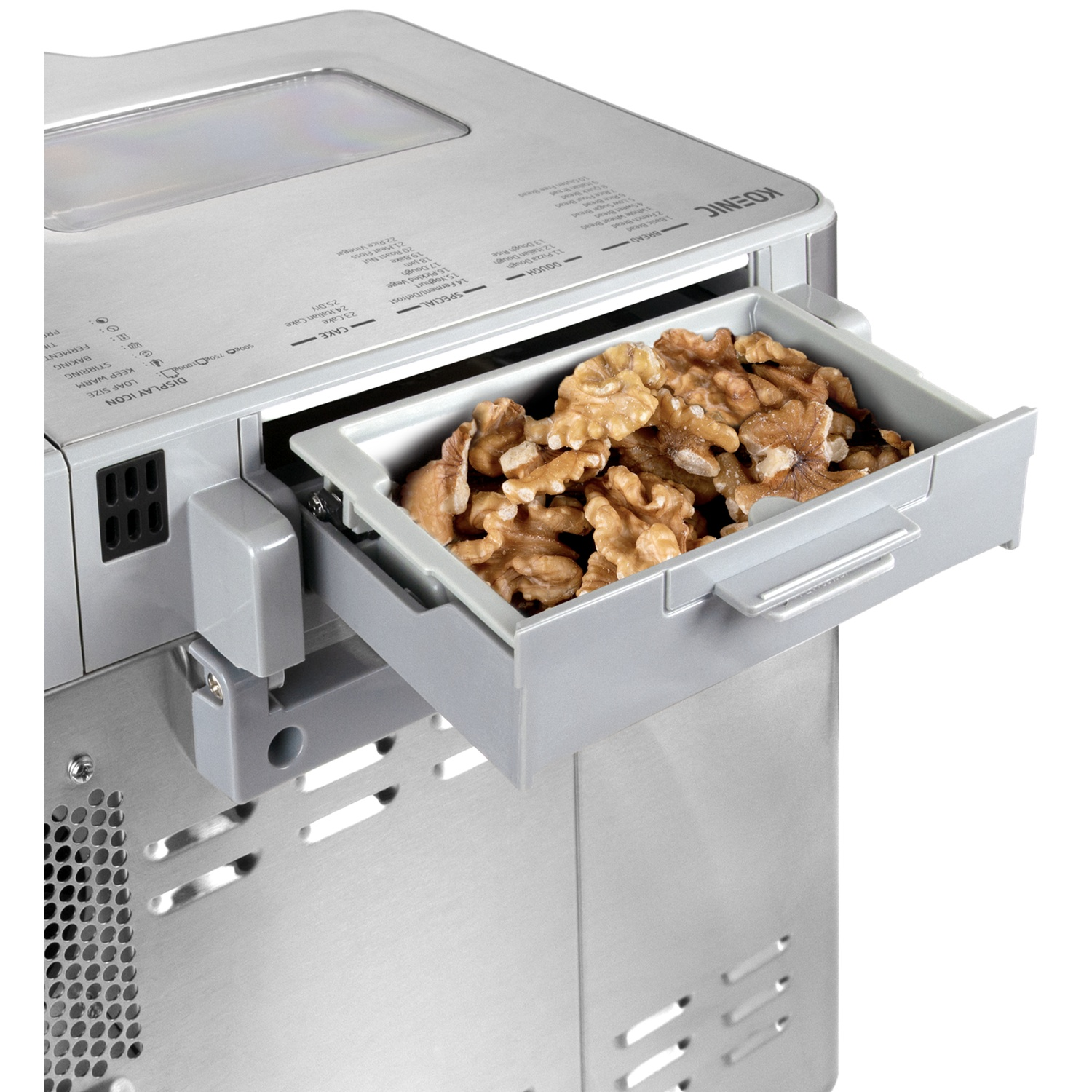 Gros plan sur une machine à pain avec un plateau de noix. La machine est argentée et le plateau gris.