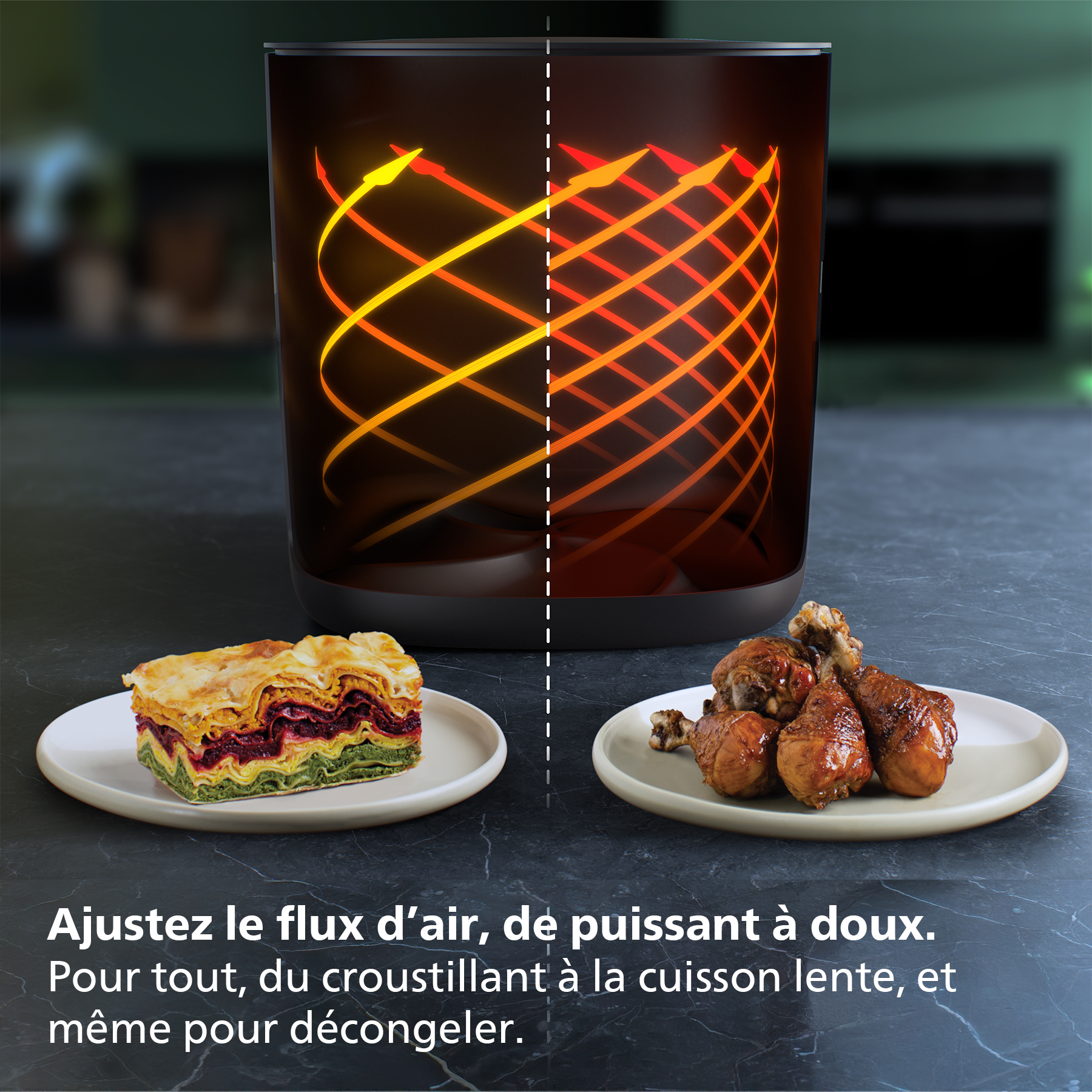 Une friteuse à air avec de la nourriture dans des assiettes. Lasagnes à gauche et cuisses de poulet cuites à droite. Élément chauffant visible.