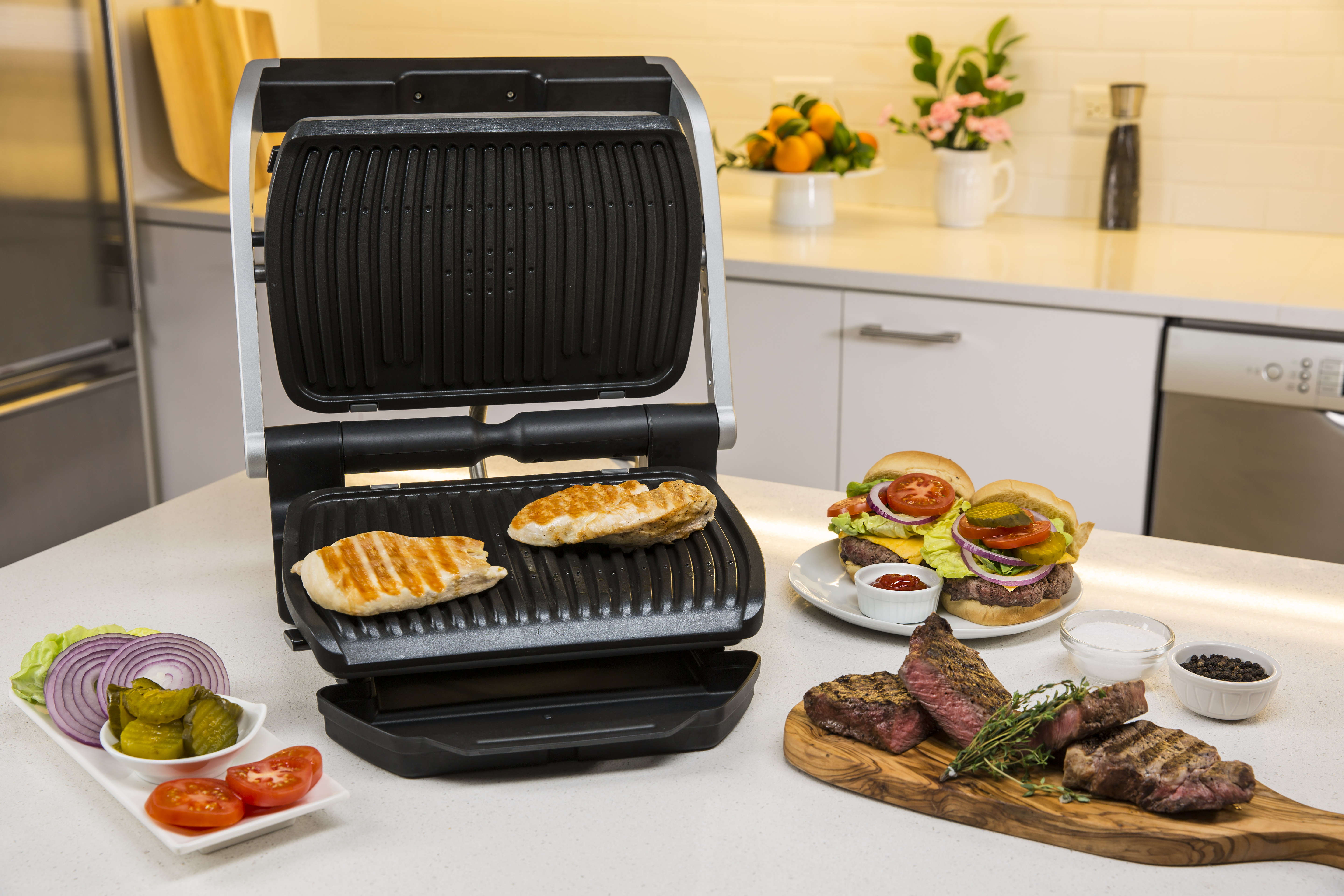 Nyitott grill csirkével. Burgerek, steak és köretek a pulton.