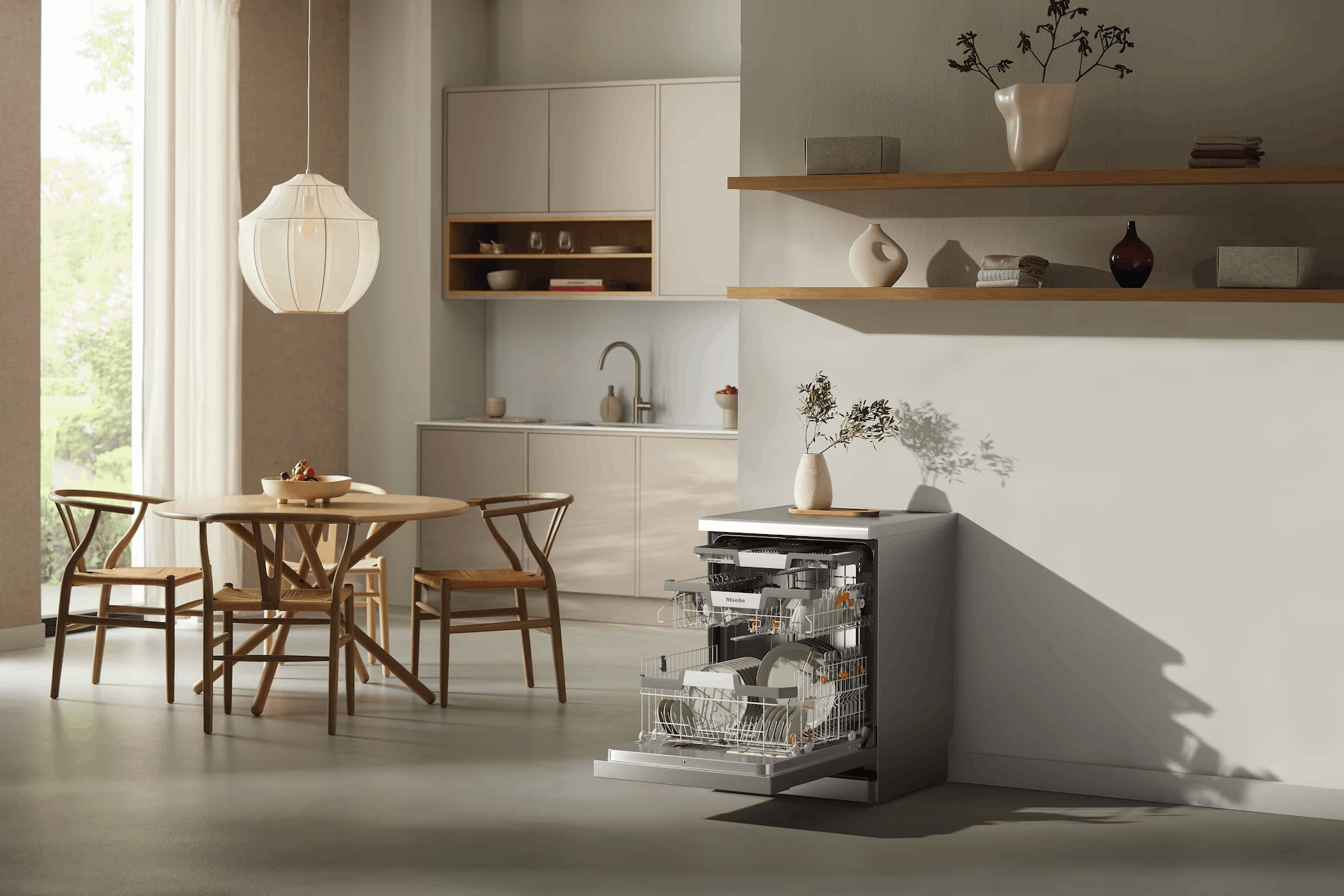 Una cocina moderna con lavavajillas abierto, mesa, sillas y estantes con objetos decorativos. Predominan los colores neutros.