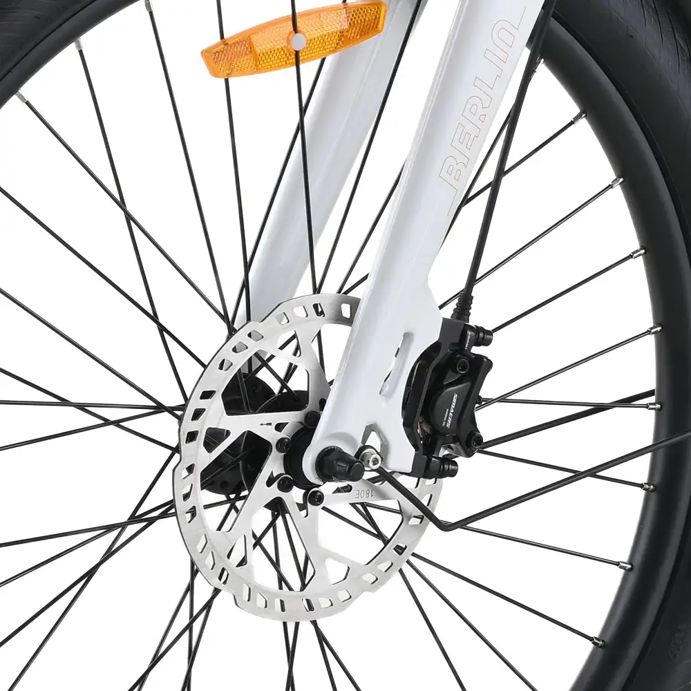 Primer plano de una rueda de bicicleta con freno de disco. Horquilla blanca, neumático negro, disco plateado y radios negros. Hay un reflector naranja en la parte superior.