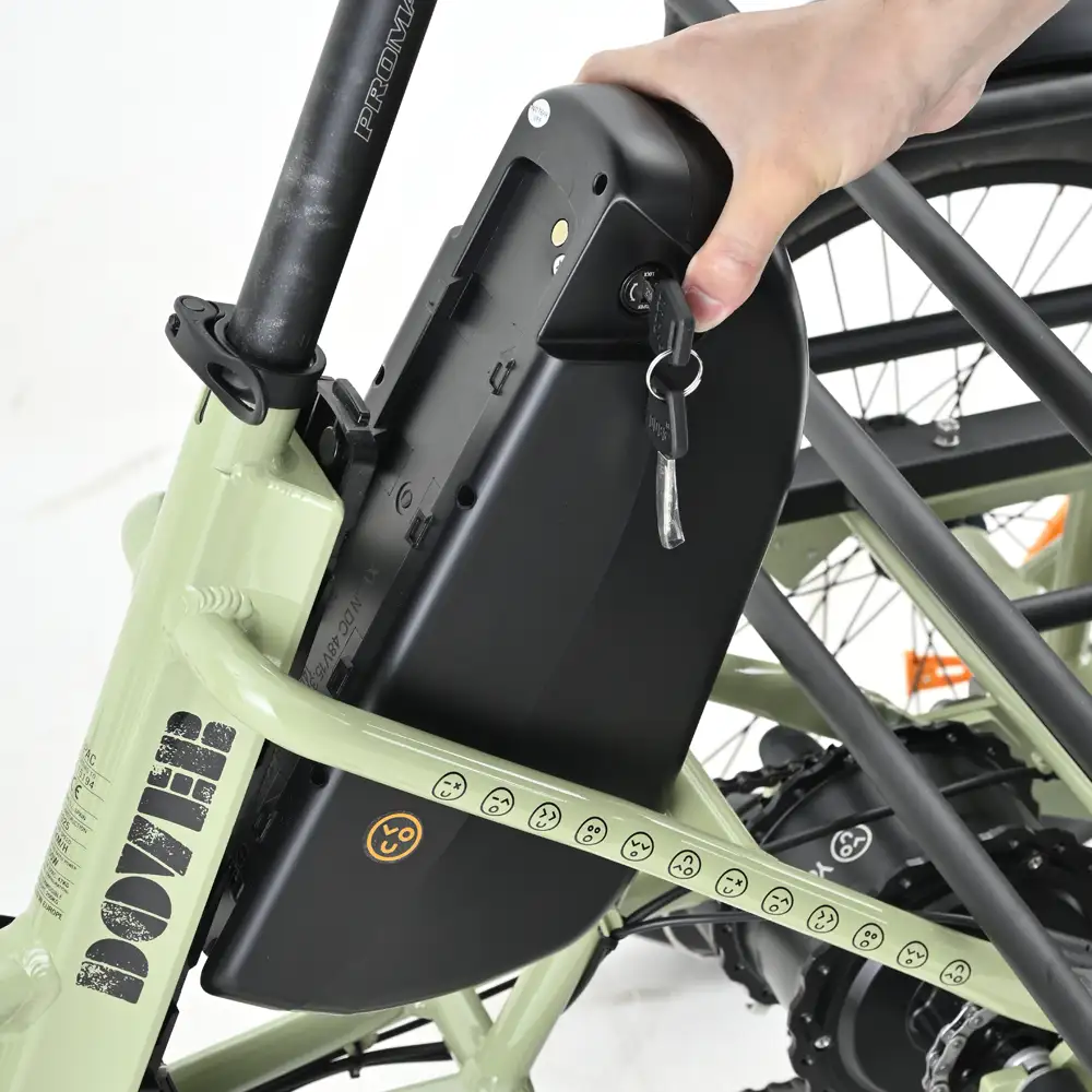 Una mano inserta una llave en una batería negra en una bicicleta eléctrica verde claro. La batería está bloqueada.