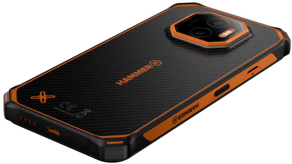 Czarny i pomarańczowy wytrzymały smartfon z wypukłością aparatu. Widoczne logo Hammer. Teksturowany tył. Szczegóły obejmują porty i przyciski.