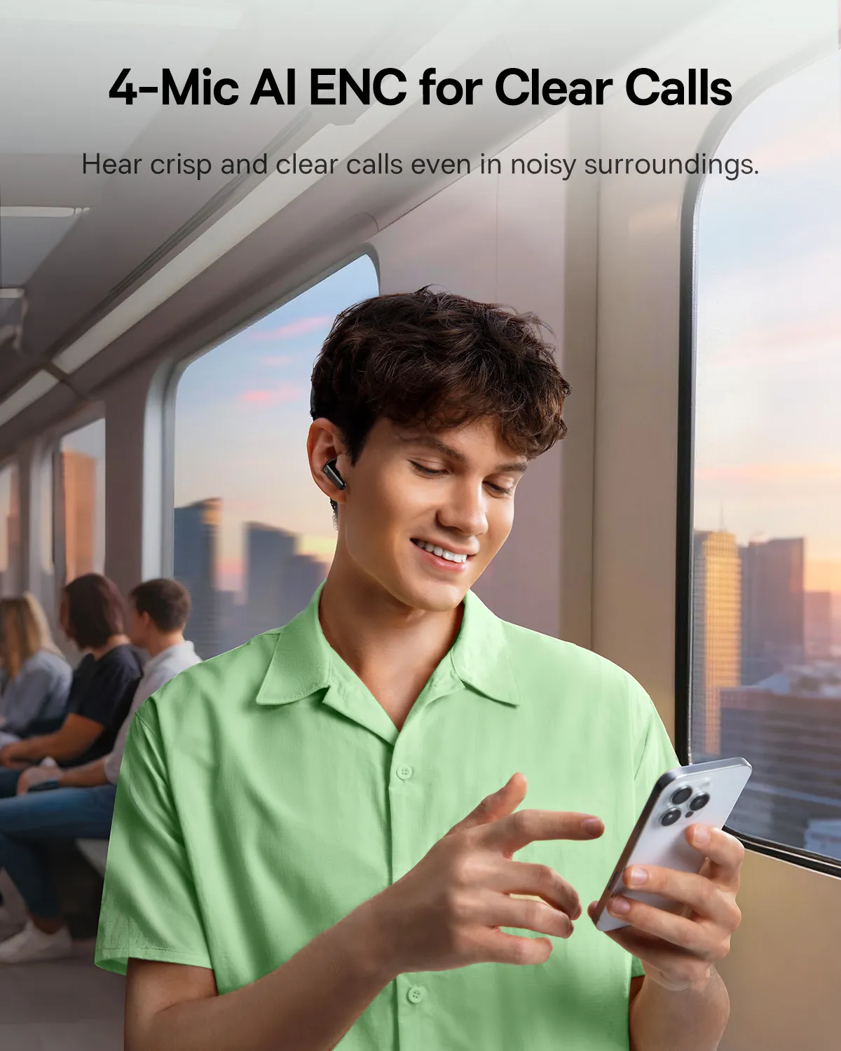 Un homme souriant portant des écouteurs et une chemise vert clair tient un téléphone dans un train. D'autres passagers sont en arrière-plan.