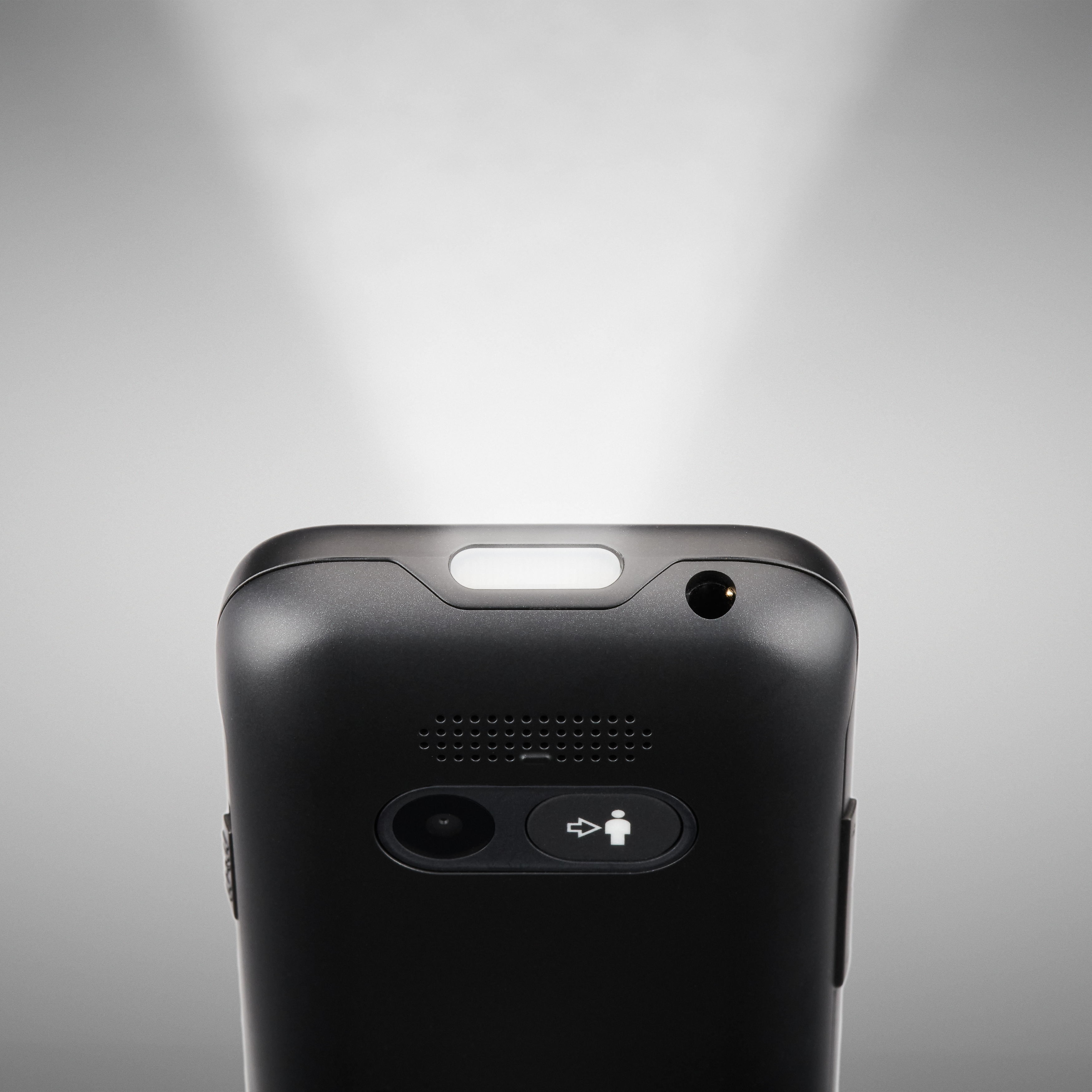 Nahaufnahme eines schwarzen Geräts, wahrscheinlich ein Telefon. Es hat oben ein Licht und verschiedene Knöpfe, darunter einen mit einem Personensymbol.