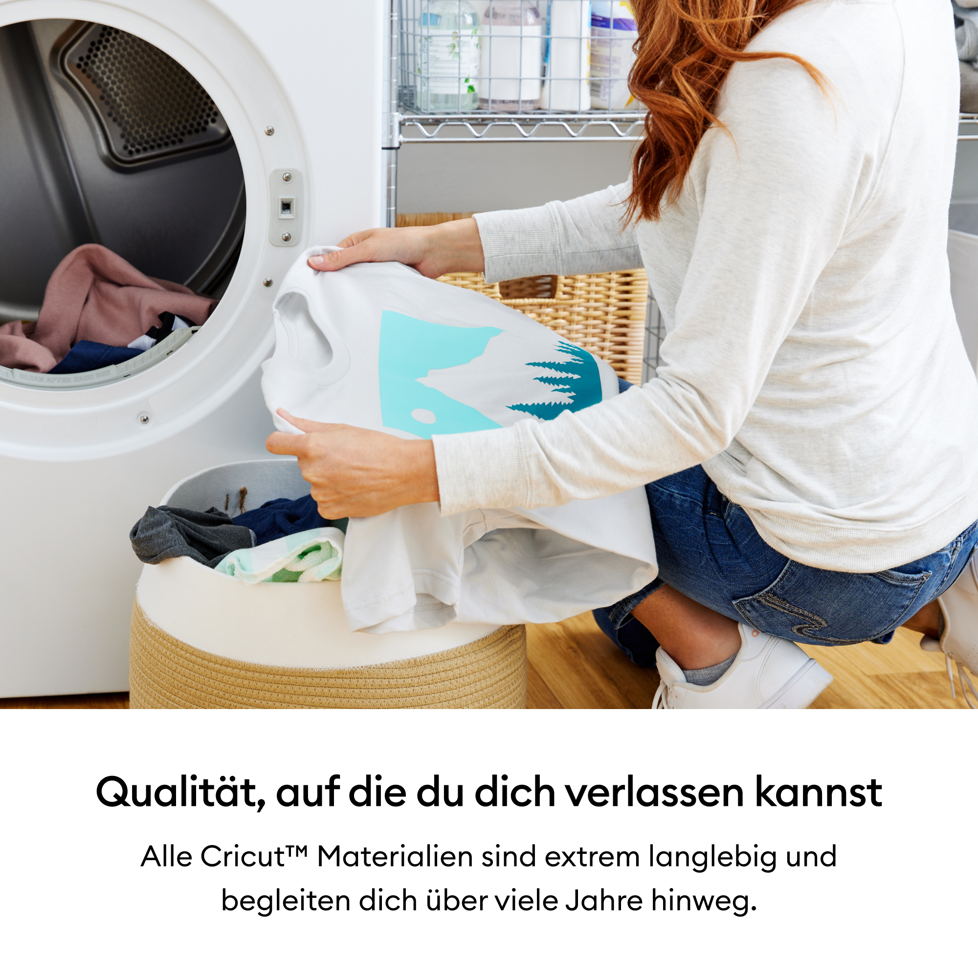 Eine Frau nimmt ein weißes Hemd mit blauem Design aus dem Trockner. Wäschekorb und Regal mit Vorräten sind im Bild.