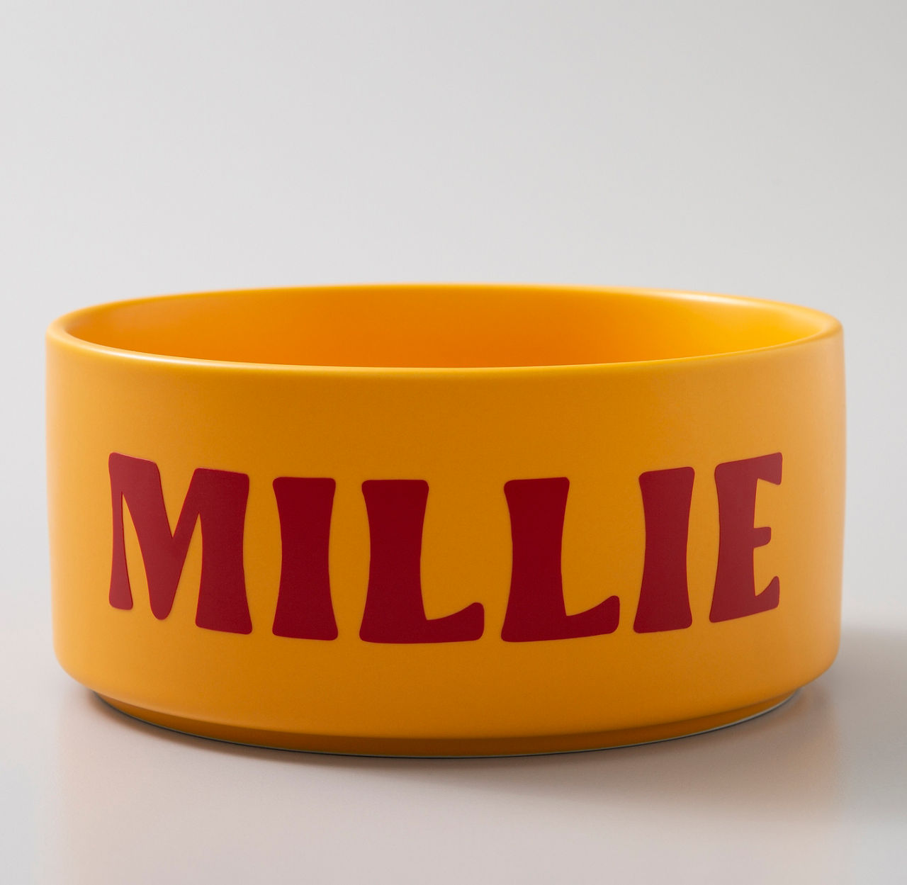 Eine orangefarbene Hundenapf mit roten Buchstaben 'MILLIE'.