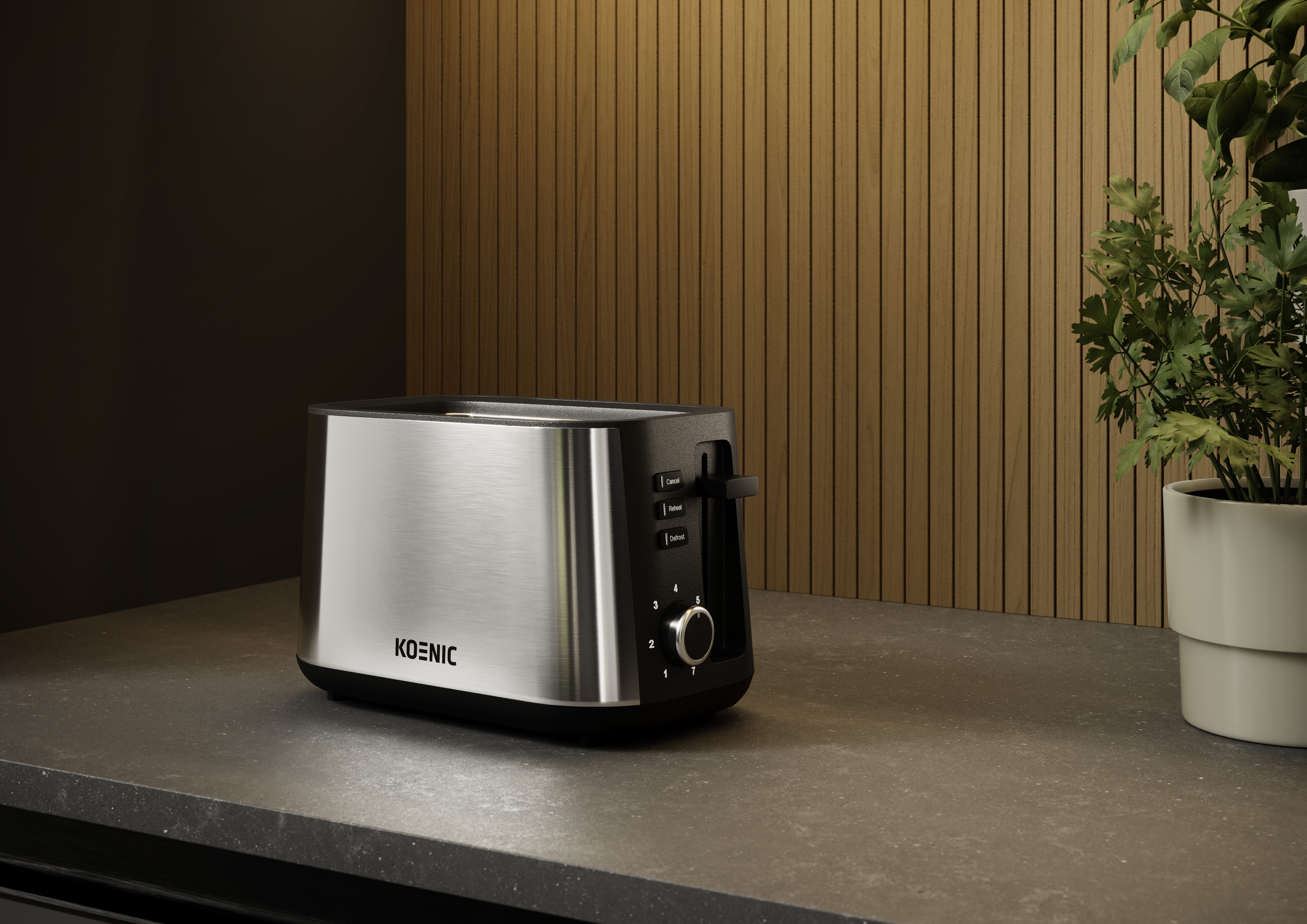 Ein Edelstahl-Koenic-Toaster steht auf einer Arbeitsplatte, mit Holzpaneel-Hintergrund. Rechts steht eine Topfpflanze.