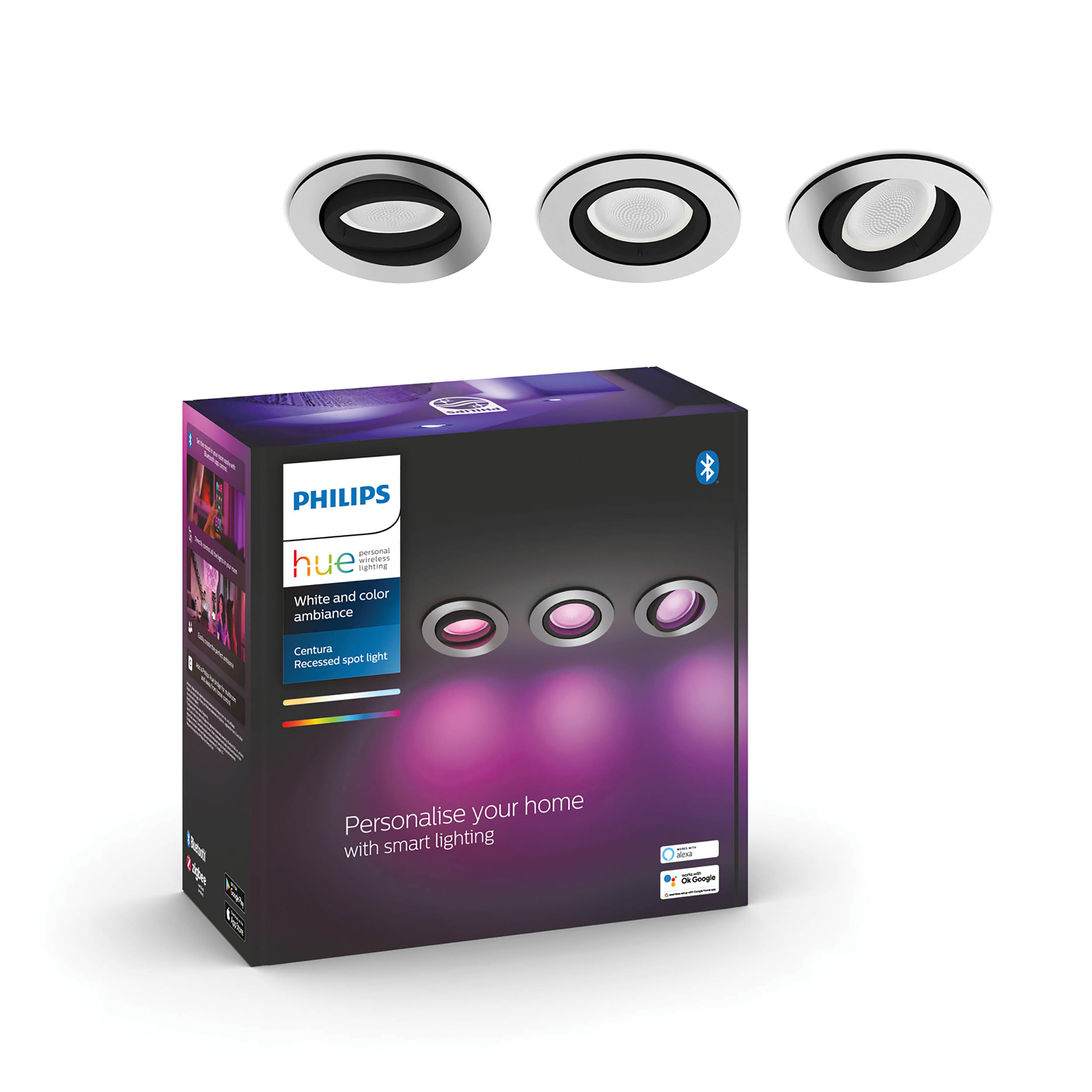 Das Bild zeigt drei Einbaustrahler und eine Schachtel mit Philips Hue-Leuchten. Die Leuchten sind silber und schwarz.
